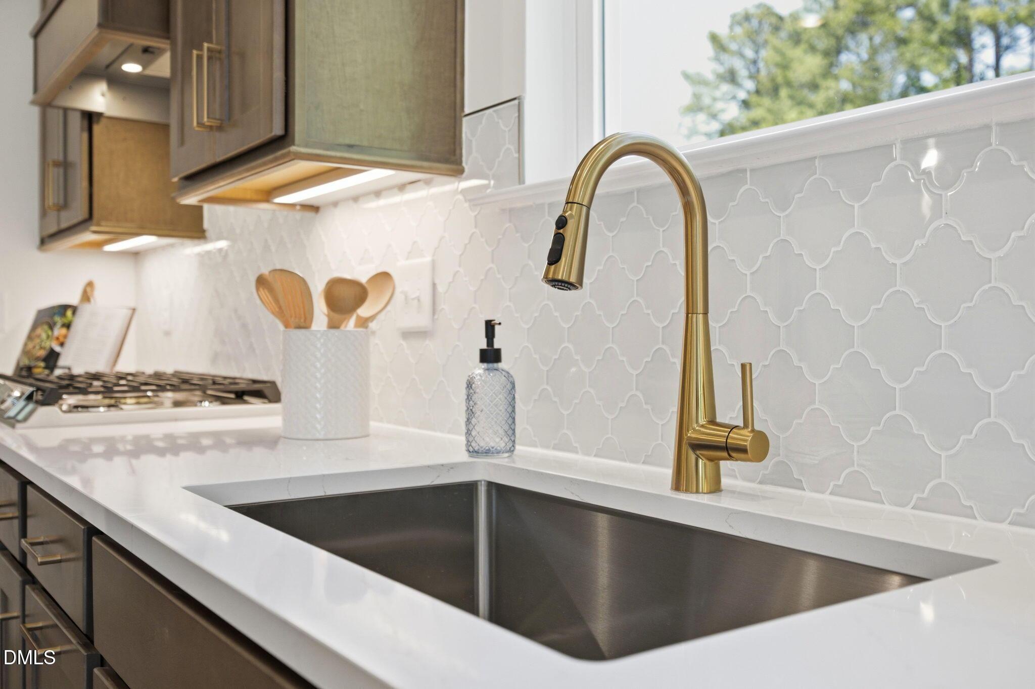 Modern kitchen sink with brass faucet, white quartz countertops, and arabesque tile backsplash in The Ashport M floor plan.