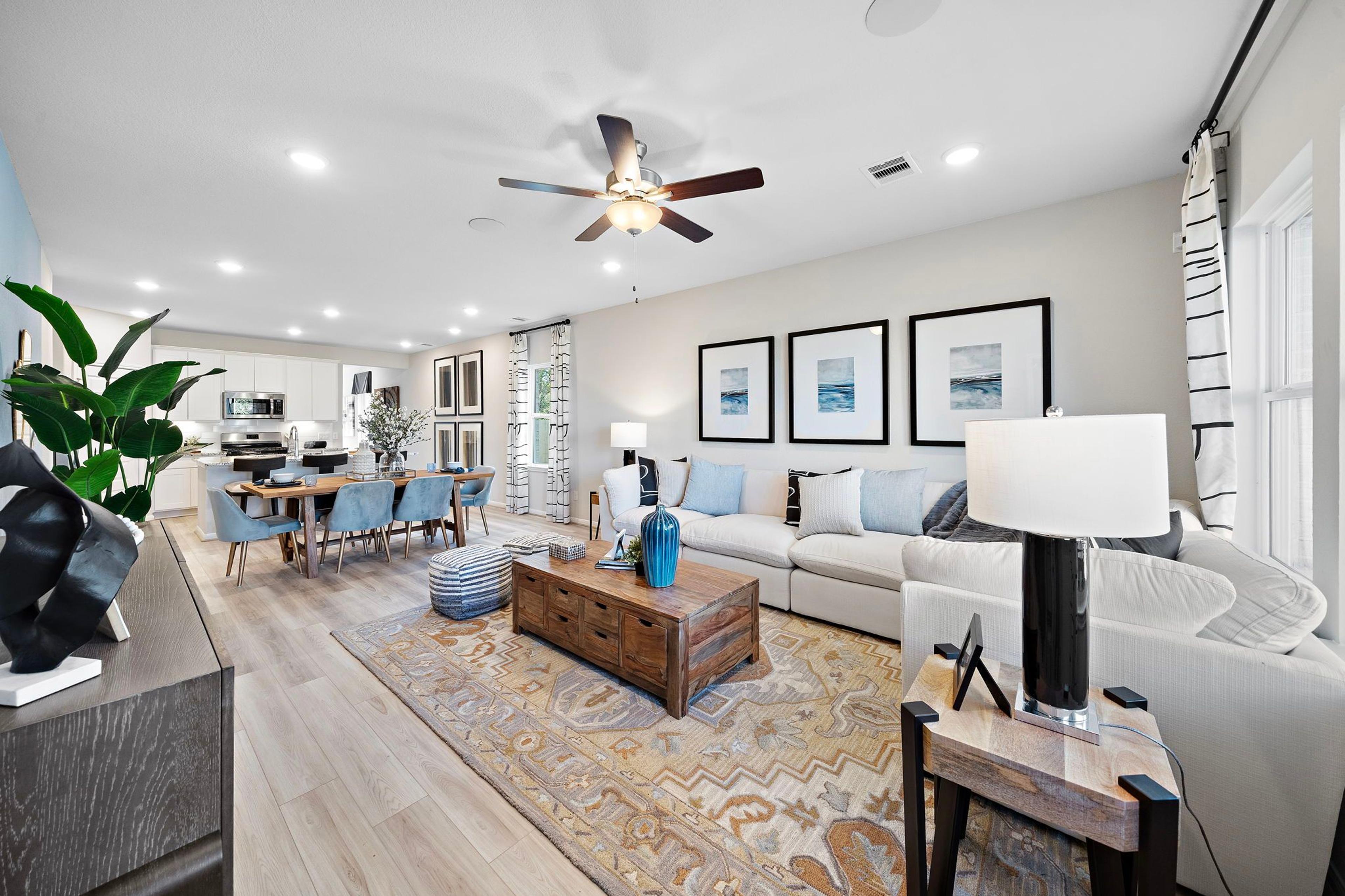 Open-concept living dining area in Heartland Texas Davidson Homes with hardwood floors white sofas blue accents and modern wall art