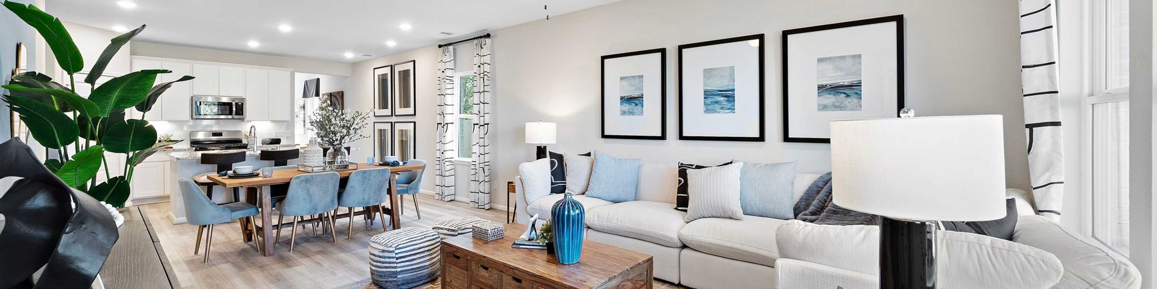 Open-concept living dining area in Heartland Texas Davidson Homes with hardwood floors white sofas blue accents and modern wall art