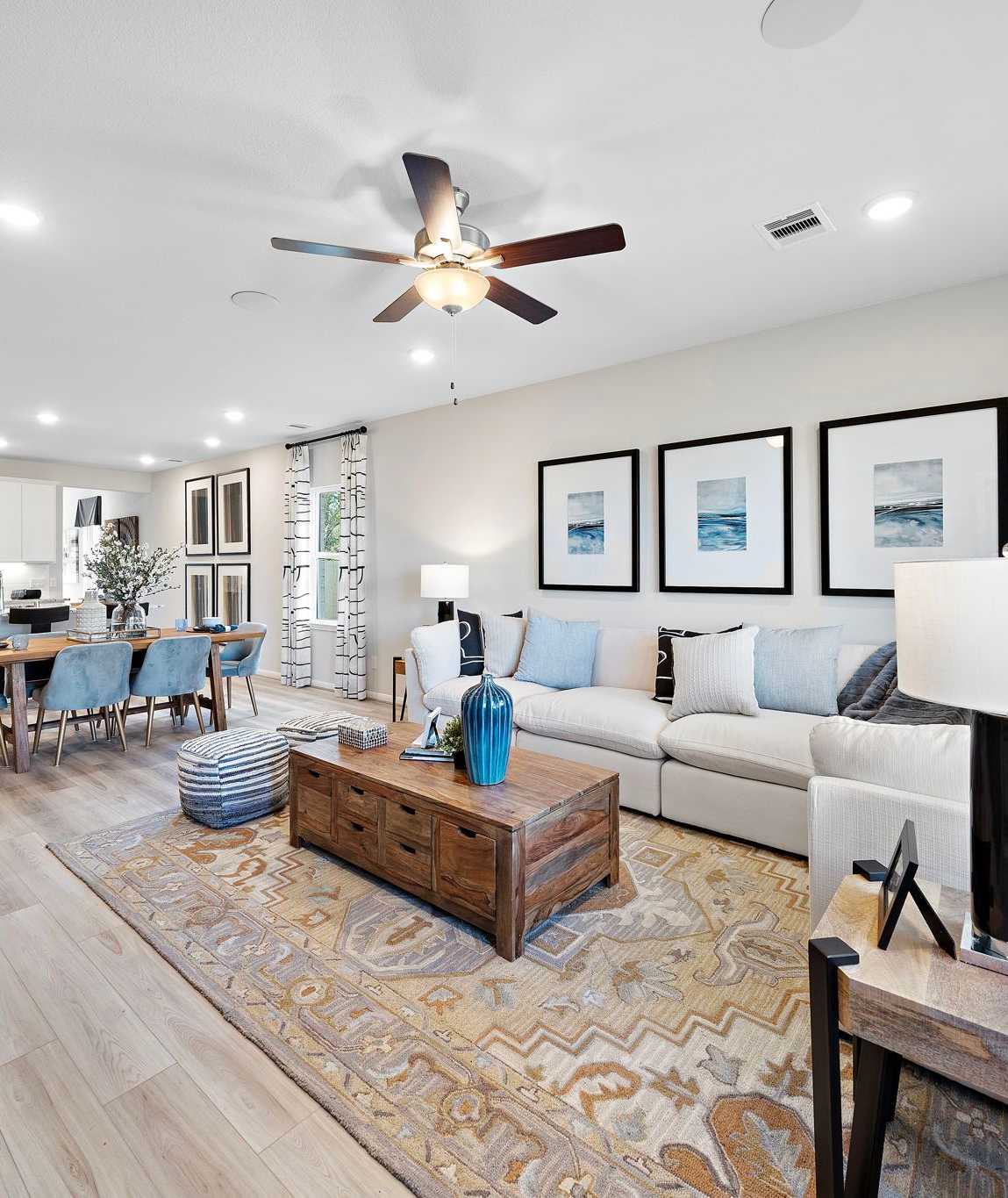 Open-concept living dining area in Heartland Texas Davidson Homes with hardwood floors white sofas blue accents and modern wall art