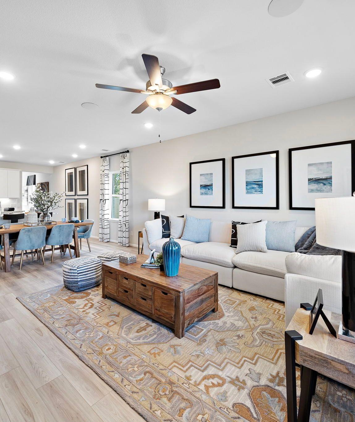 Open-concept living dining area in Heartland Texas Davidson Homes with hardwood floors white sofas blue accents and modern wall art