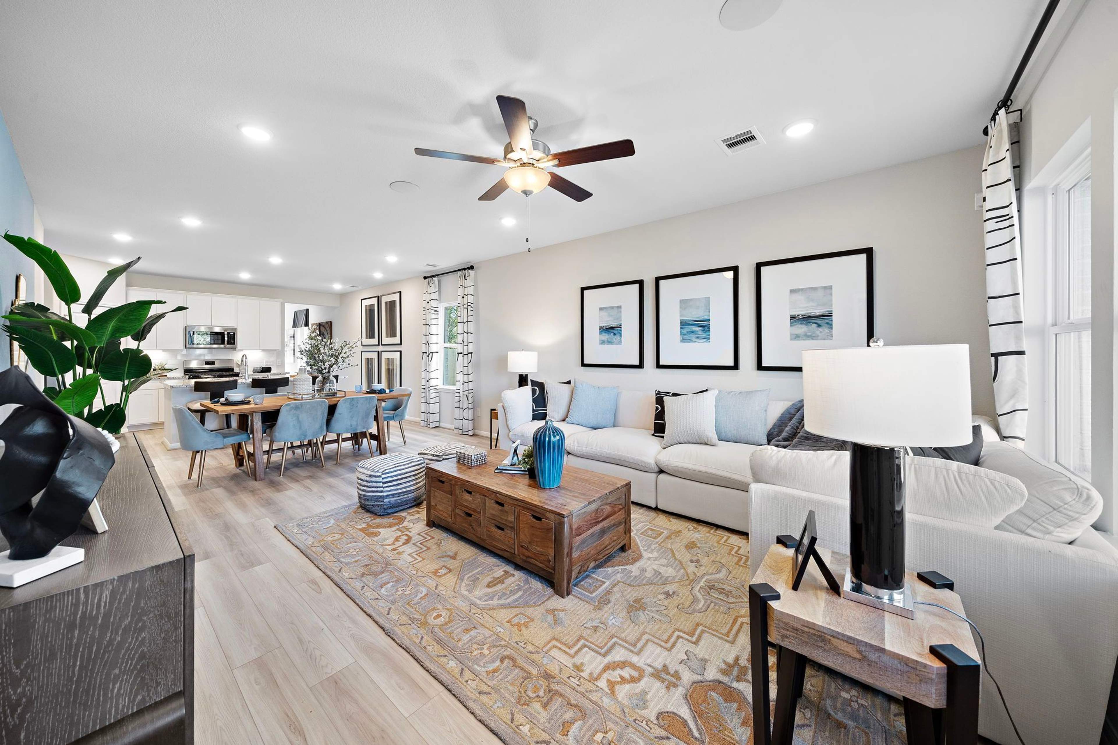 Open-concept living dining area in Heartland Texas Davidson Homes with hardwood floors white sofas blue accents and modern wall art