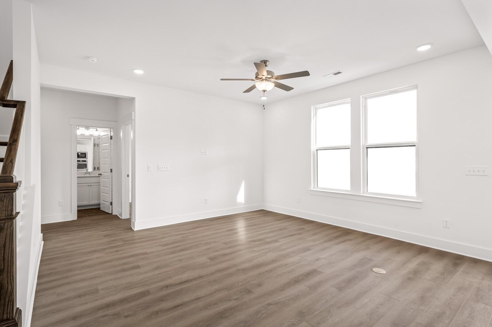 Bright, spacious living area with ceiling fan and wood-style flooring in The Willow D floor plan, Mt. Juliet, Tennessee.