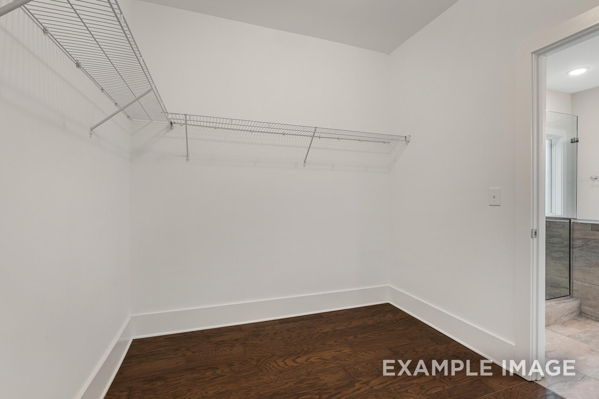 Spacious walk-in closet in The Rockford master suite with wire shelving, hardwood floors, and bathroom access, Davidson Homes