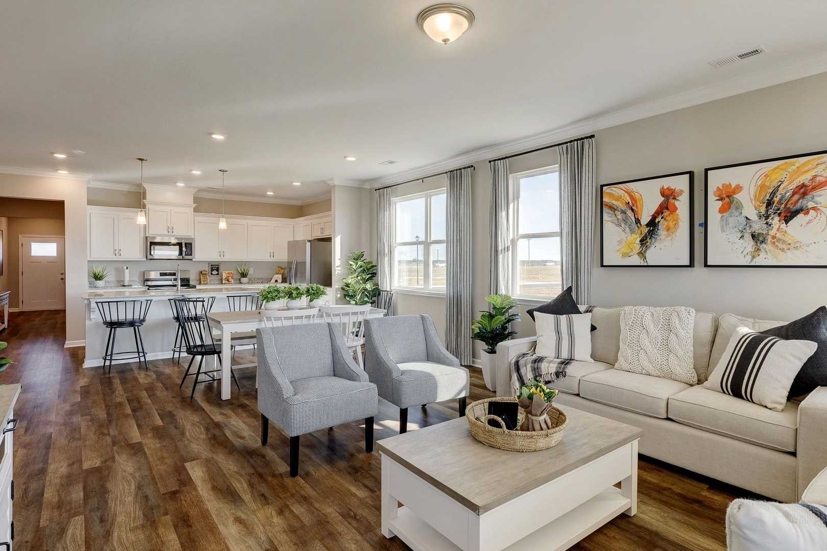 Spacious open-concept kitchen and living room at Carroll Green in Harvest AL with hardwood floors, white cabinets, and gray sofa