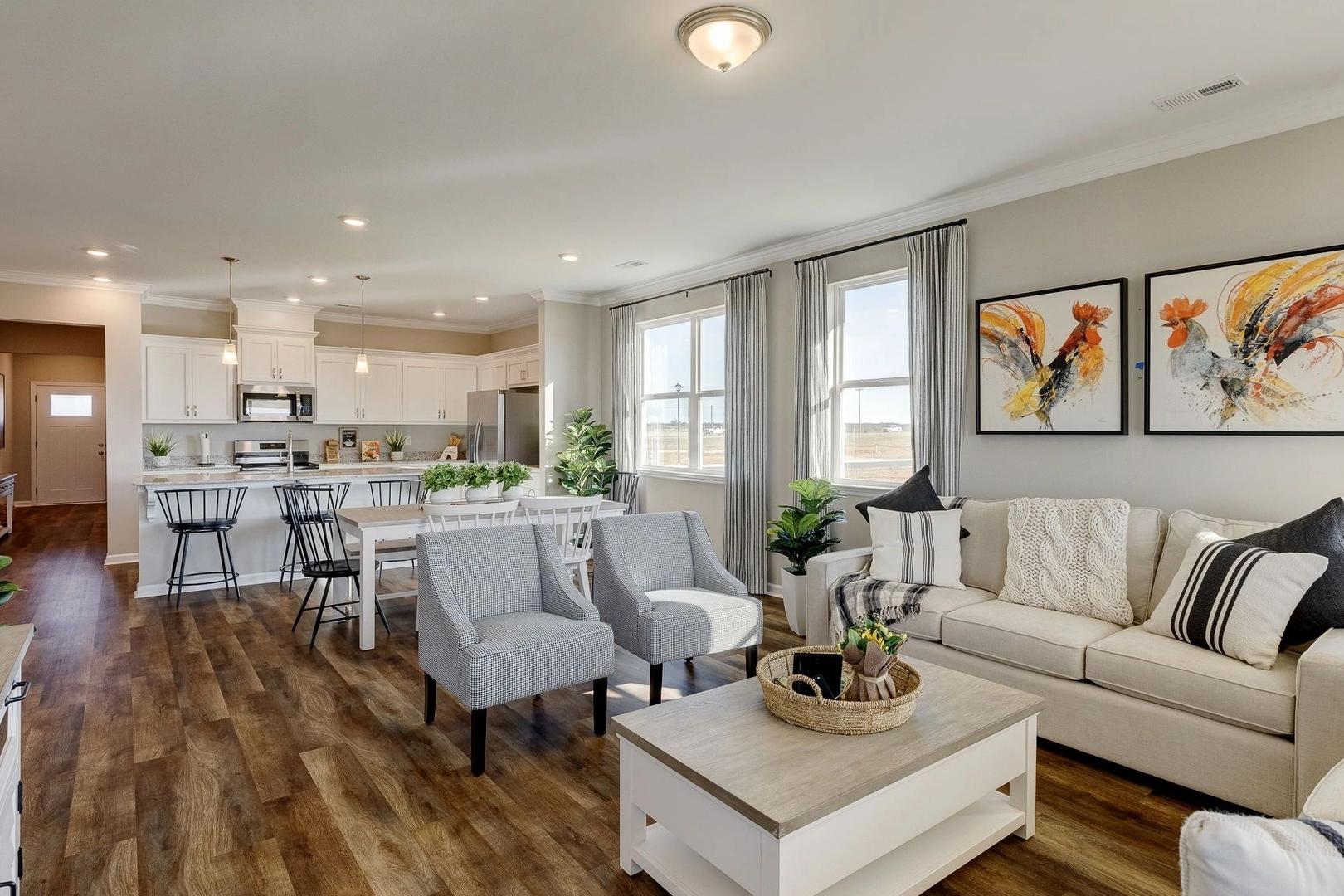 Spacious open-concept kitchen and living room at Carroll Green in Harvest AL with hardwood floors, white cabinets, and gray sofa