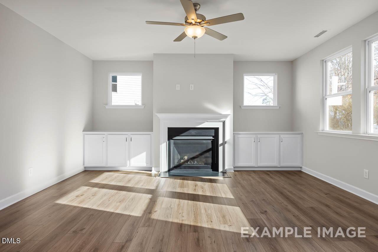 Living room with fireplace, built-in cabinets, and ceiling fan in The Hickory II B plan by Davidson Homes in Aberdeen, NC.