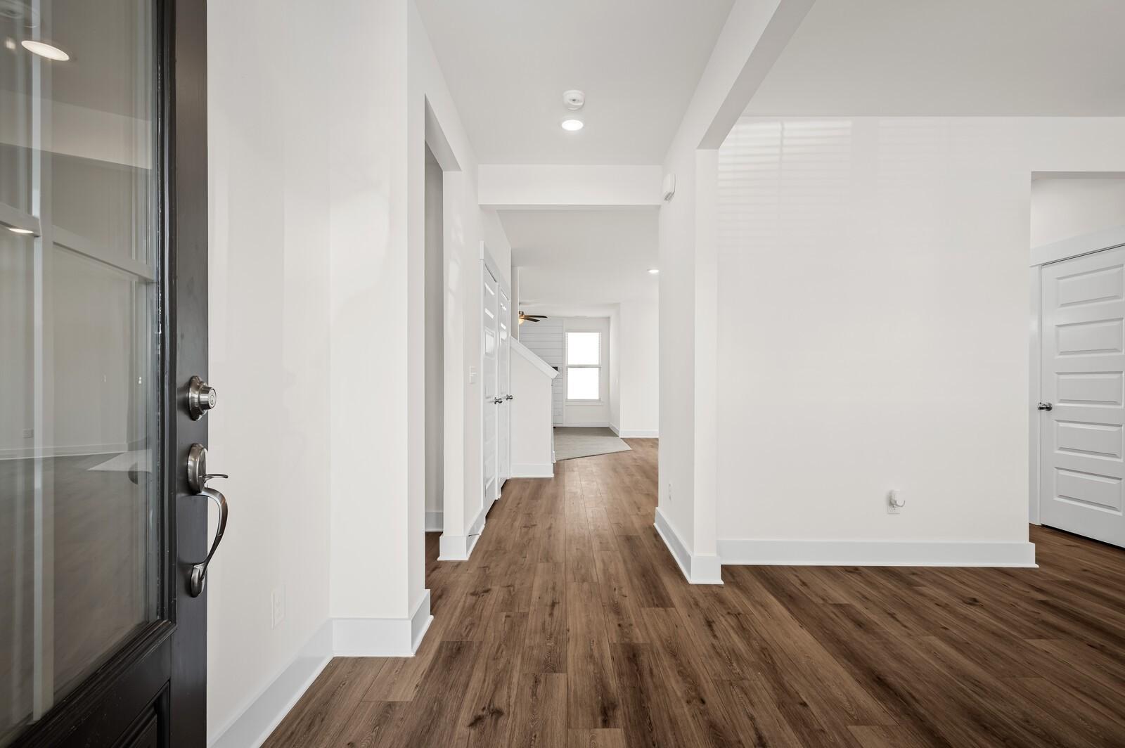 Bright foyer entrance with wood-look flooring and modern white interior in The Ash A floor plan at Woods Crossing, Gallatin.