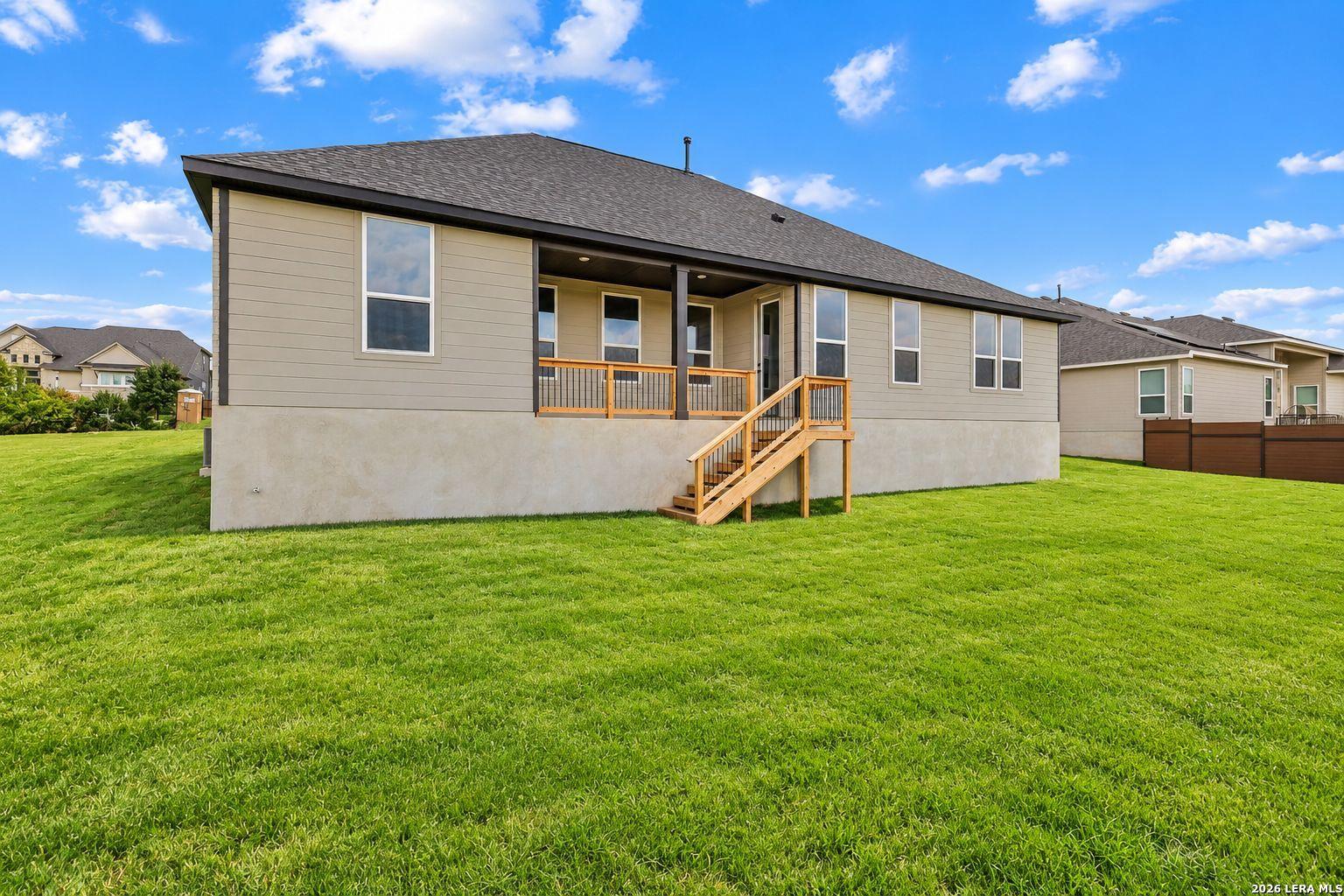 Covered back patio with wooden stairs overlooking spacious green yard in Davidson Homes Foster E, Potranco Oaks, Castroville, Texas