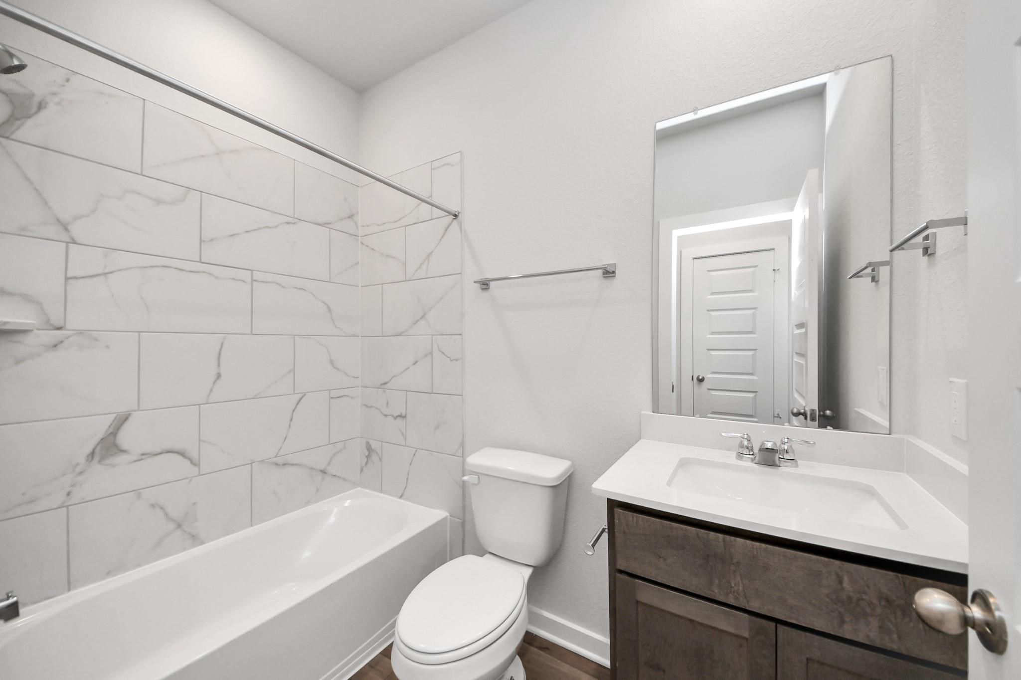 Modern bathroom with marble-style tile shower and vanity in The Sabine E floor plan at Liberty Estates, Cleveland, Texas.