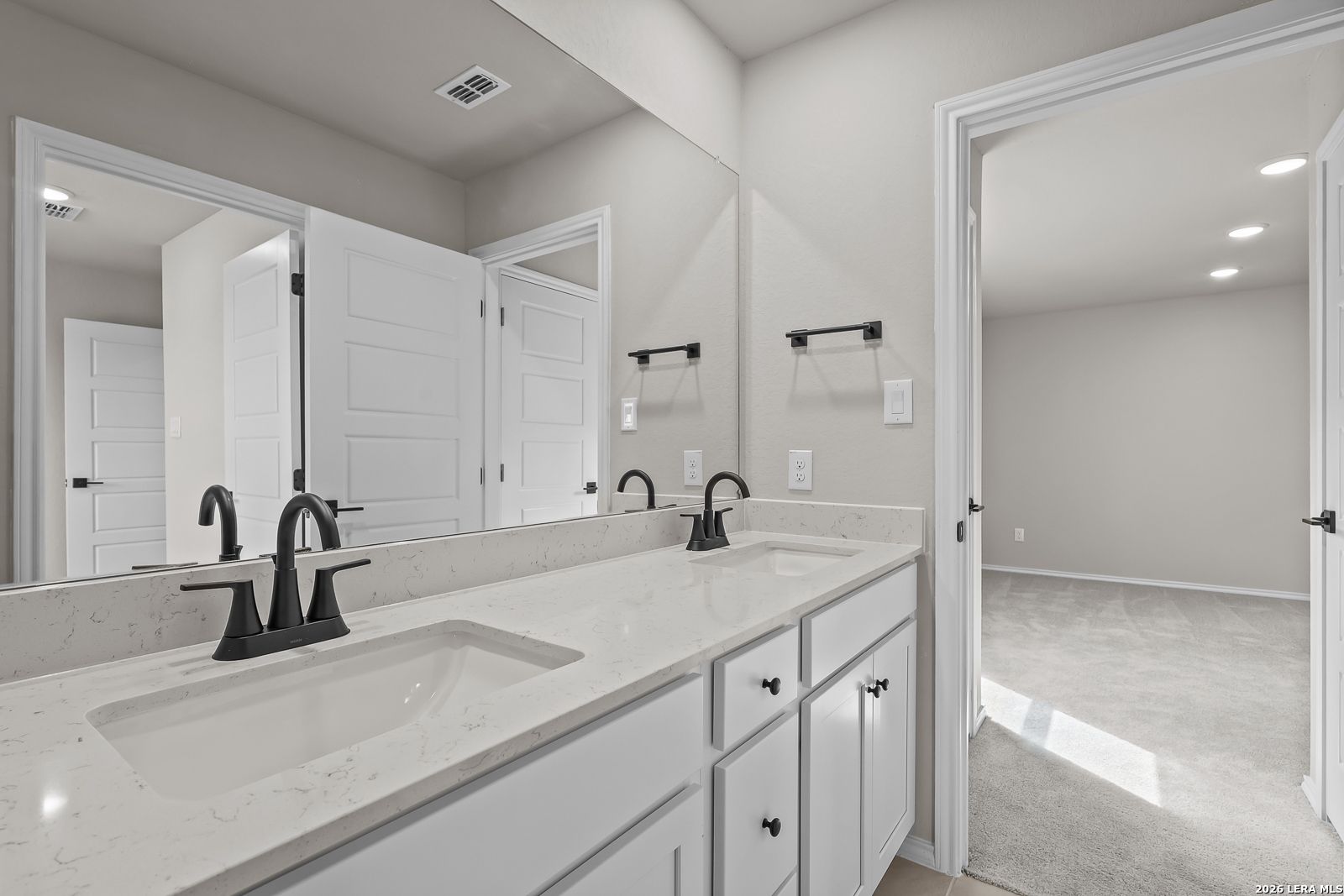 Double vanity bathroom with white cabinets, quartz countertops, and matte black faucets in Davidson Homes The Sequoia C, Royal Crest San Antonio