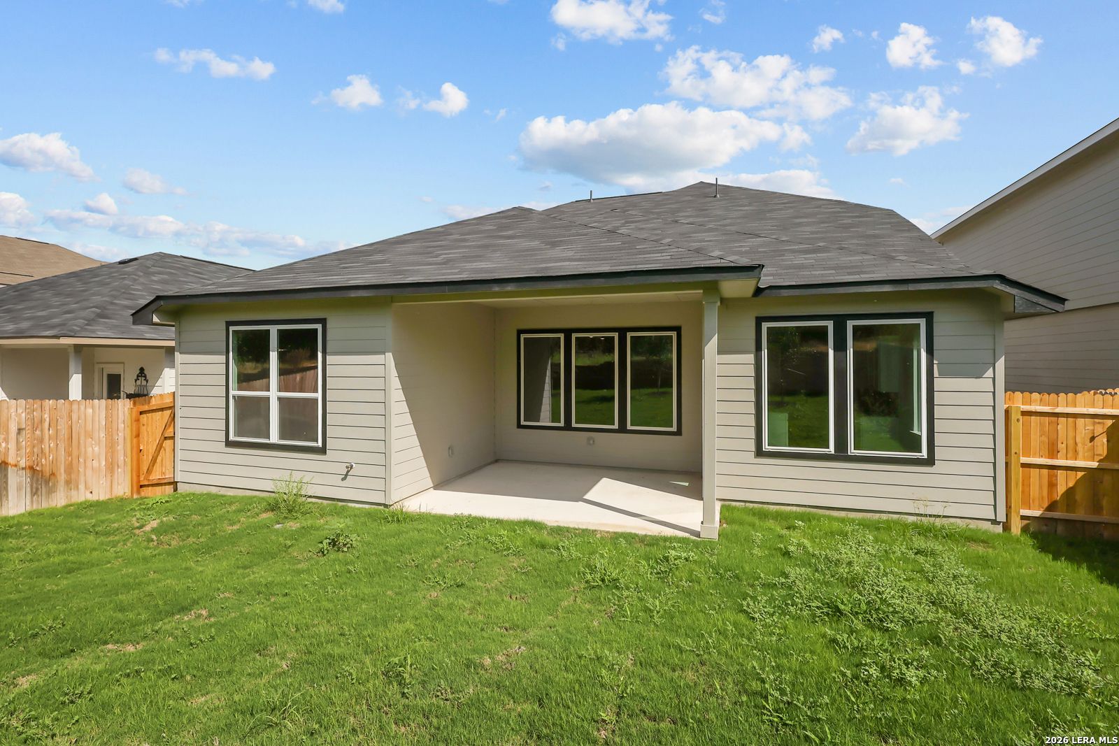 Covered patio with black-framed windows and fenced backyard at Davidson Homes The Sequoia C in Royal Crest, San Antonio, Texas