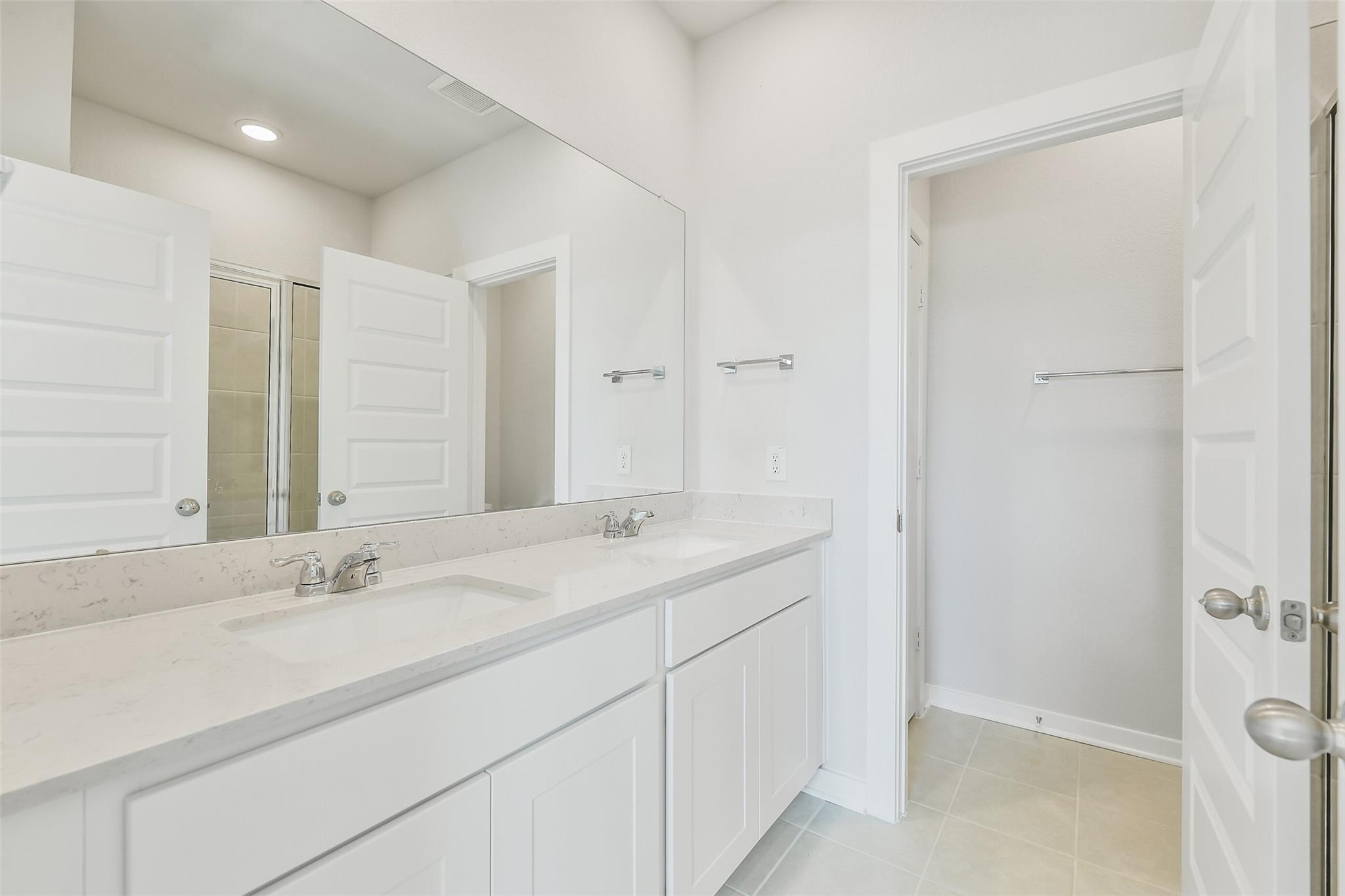 Modern master bathroom double vanity with quartz counters, large mirror, and glass shower in Davidson Homes The Frio G, Conroe, Texas