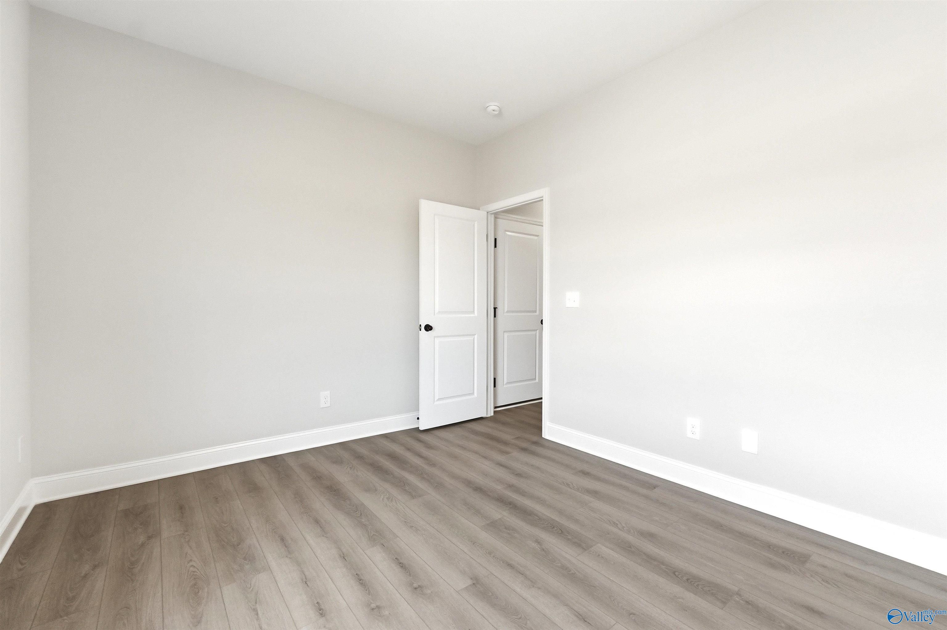 Bright secondary bedroom with wood-look flooring and white doors in The Daphne F plan at Berry Cove in New Market, AL.
