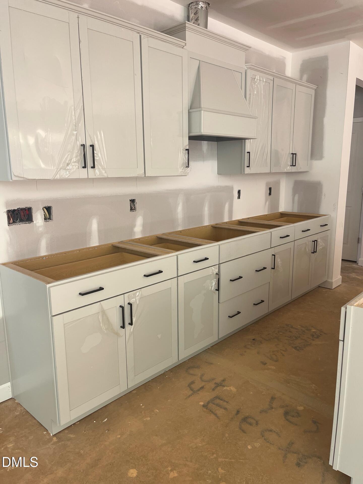 Unfinished white shaker kitchen cabinets with range hood and plywood flooring in The Beech B by Davidson Homes, Wake Forest, NC