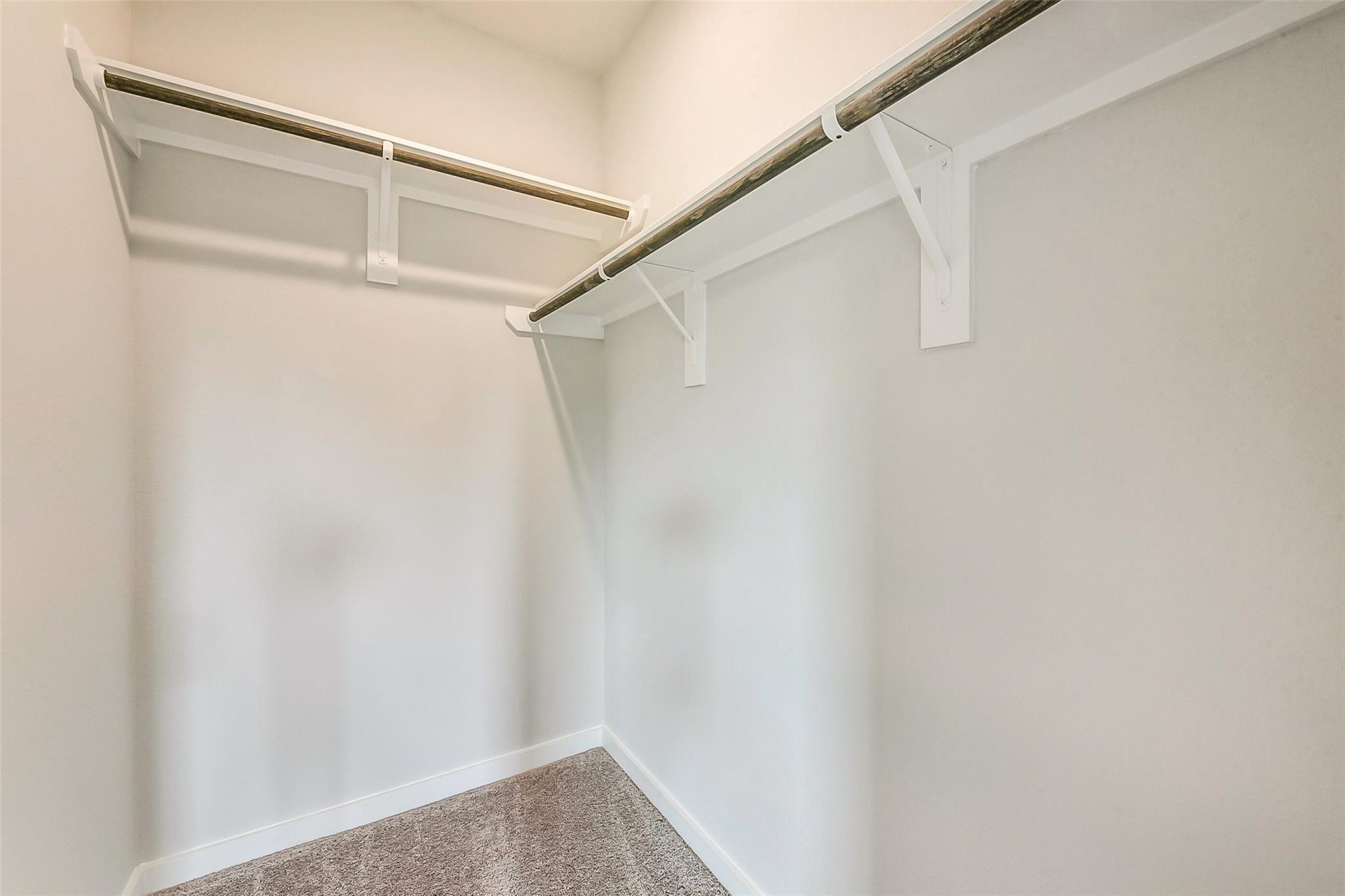 Spacious walk-in closet with white shelves and hanging rods in master suite, Davidson Homes The Comal G, Dayton, Texas