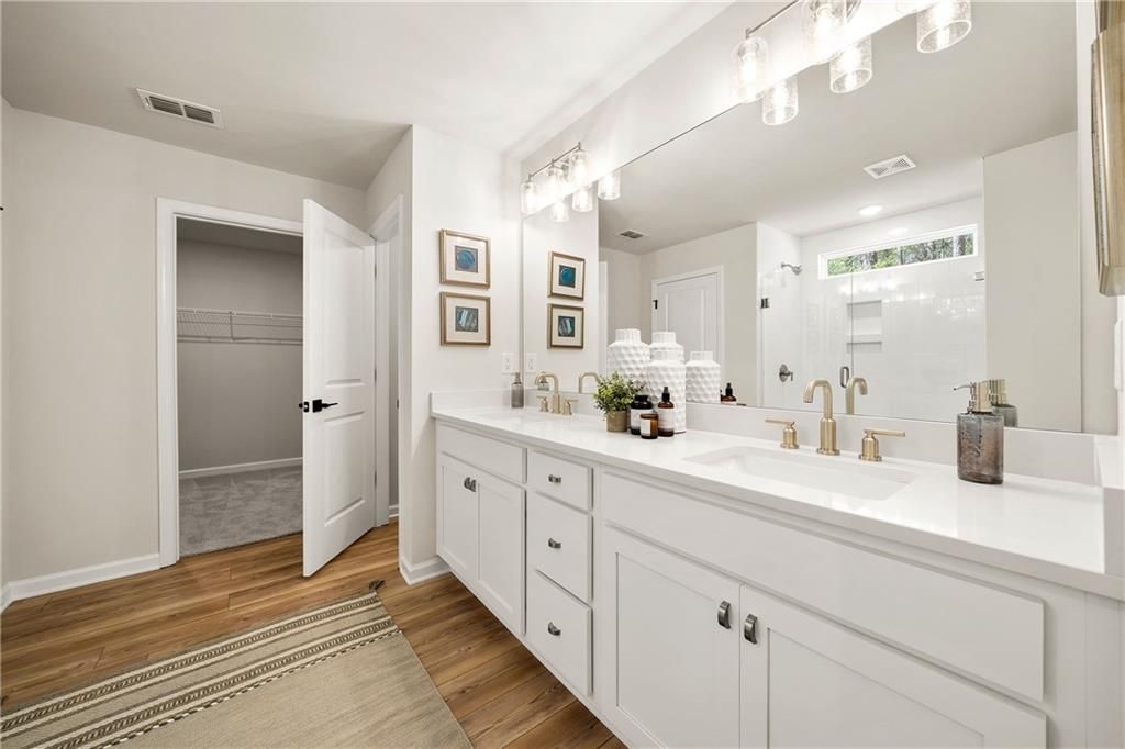 Modern master bathroom with white double vanity, large mirror, walk-in shower, and closet in Davidson Homes The Willow B, Riverwood, Dallas, Georgia