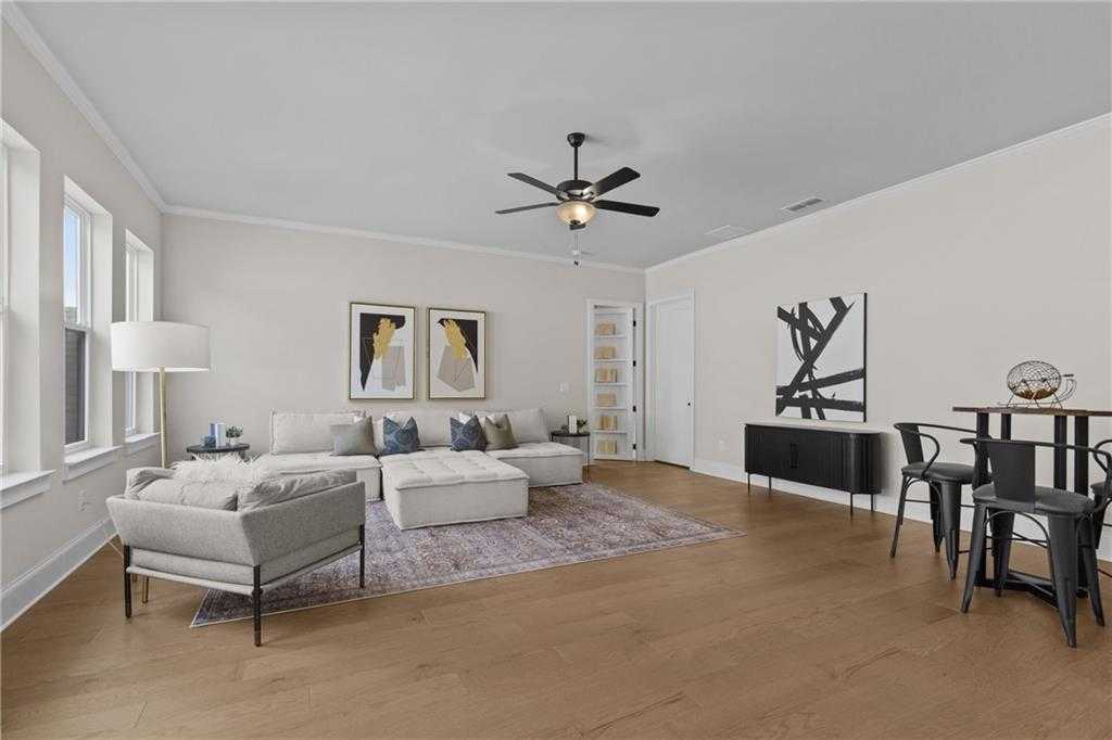 Modern living room with beige L-shaped sofa, abstract wall art, ceiling fan, and bar stools on hardwood floors in Woodstock, Georgia home