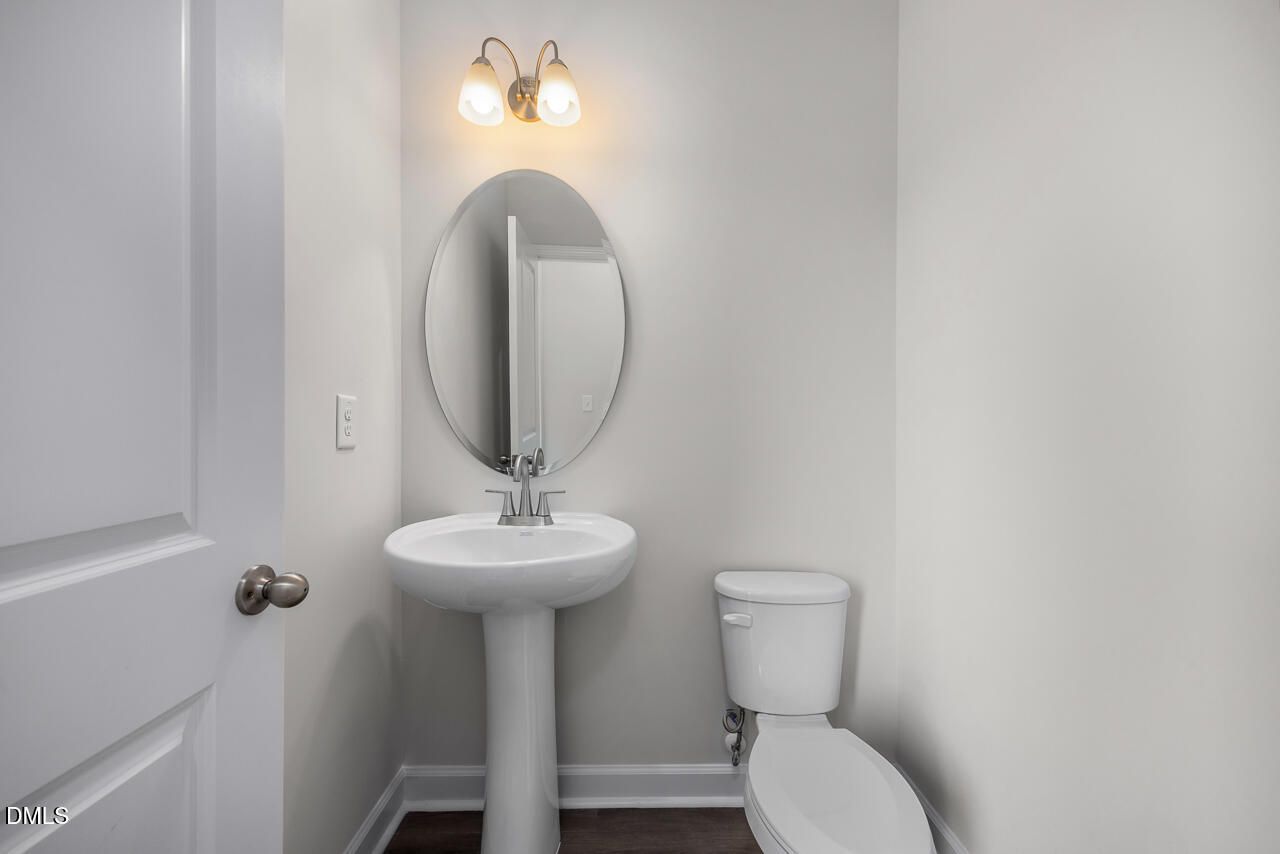 Modern powder room with pedestal sink and oval mirror in The Mitchell Interior floor plan at Forestville Yard Townhomes.