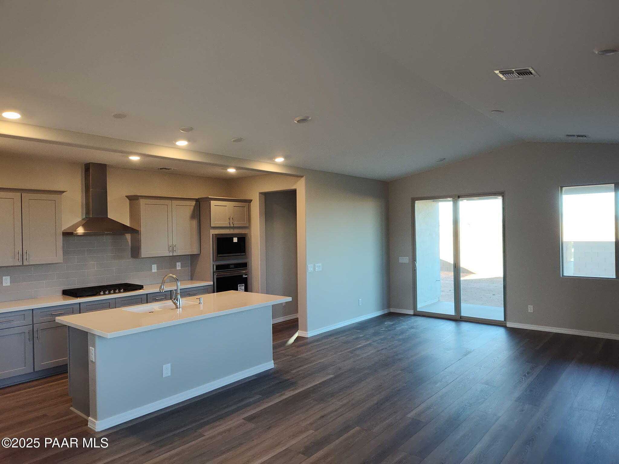 Open-concept kitchen with beige cabinets, stainless appliances, and large island flowing into living room with sliding doors in Davidson Homes The Frontier A, Prescott Valley, AZ