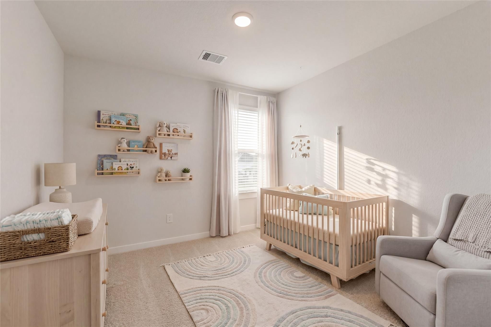 Cozy nursery with white wooden crib, changing station, rocking chair, and floating shelves in Davidson Homes The Brazos E, Cleveland, TX