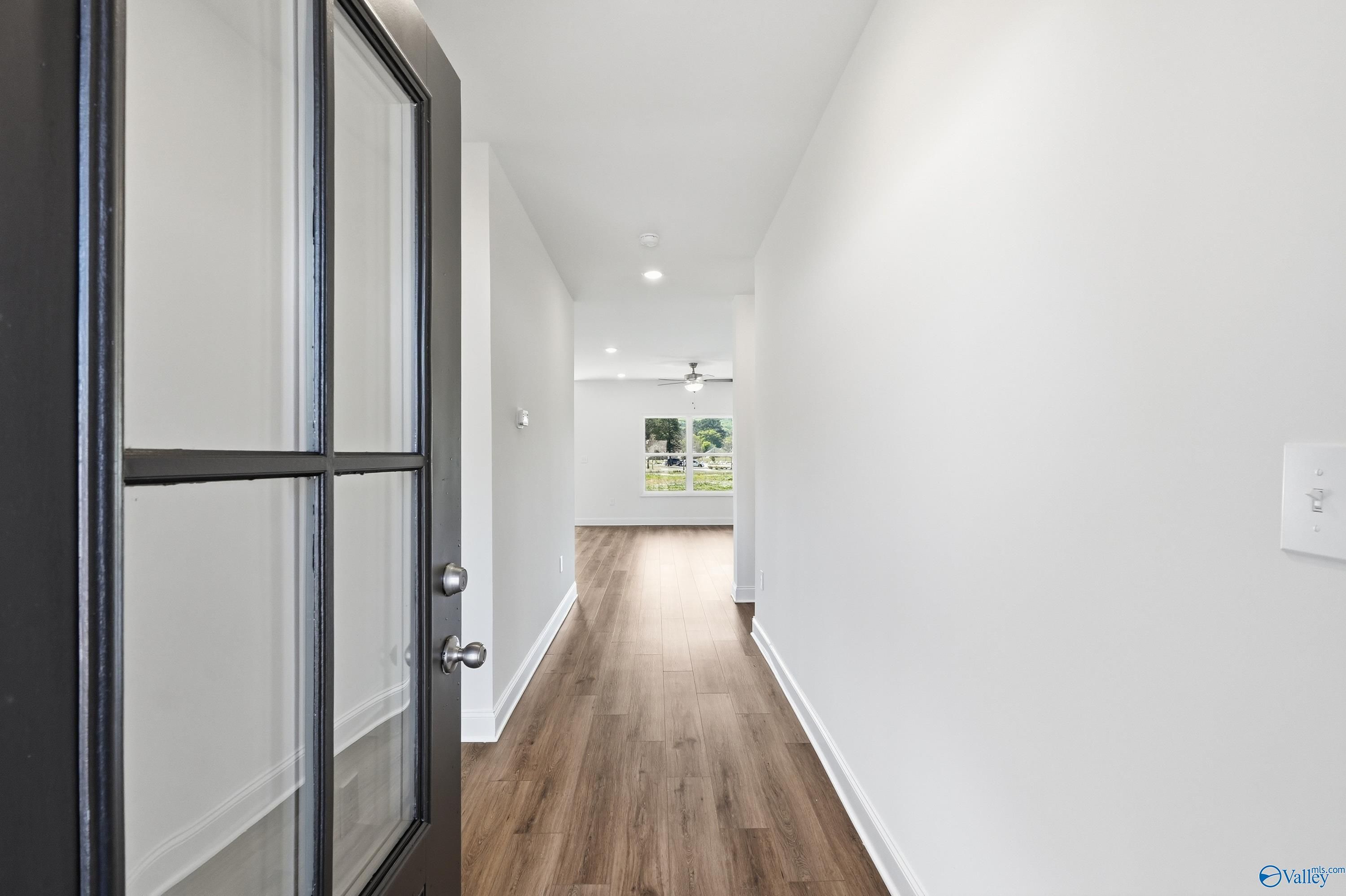 Bright entry hallway with open black glass door, luxury vinyl plank floors, recessed lights, and garden window in The Asheville home, Huntsville AL
