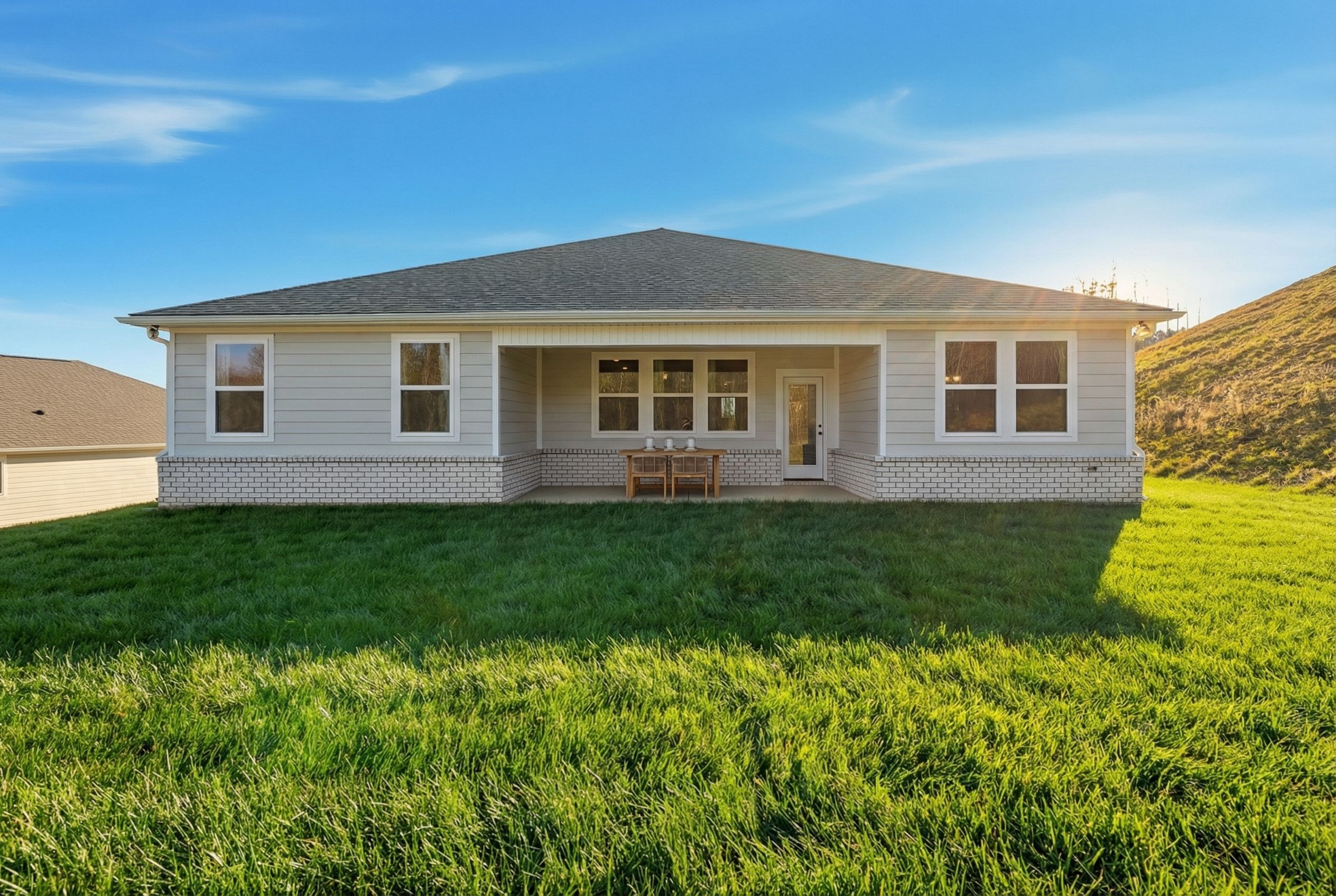 Covered rear porch of new Davidson home in Noble Ridge, Cullman Alabama with large windows, French doors, patio table and lush green lawn