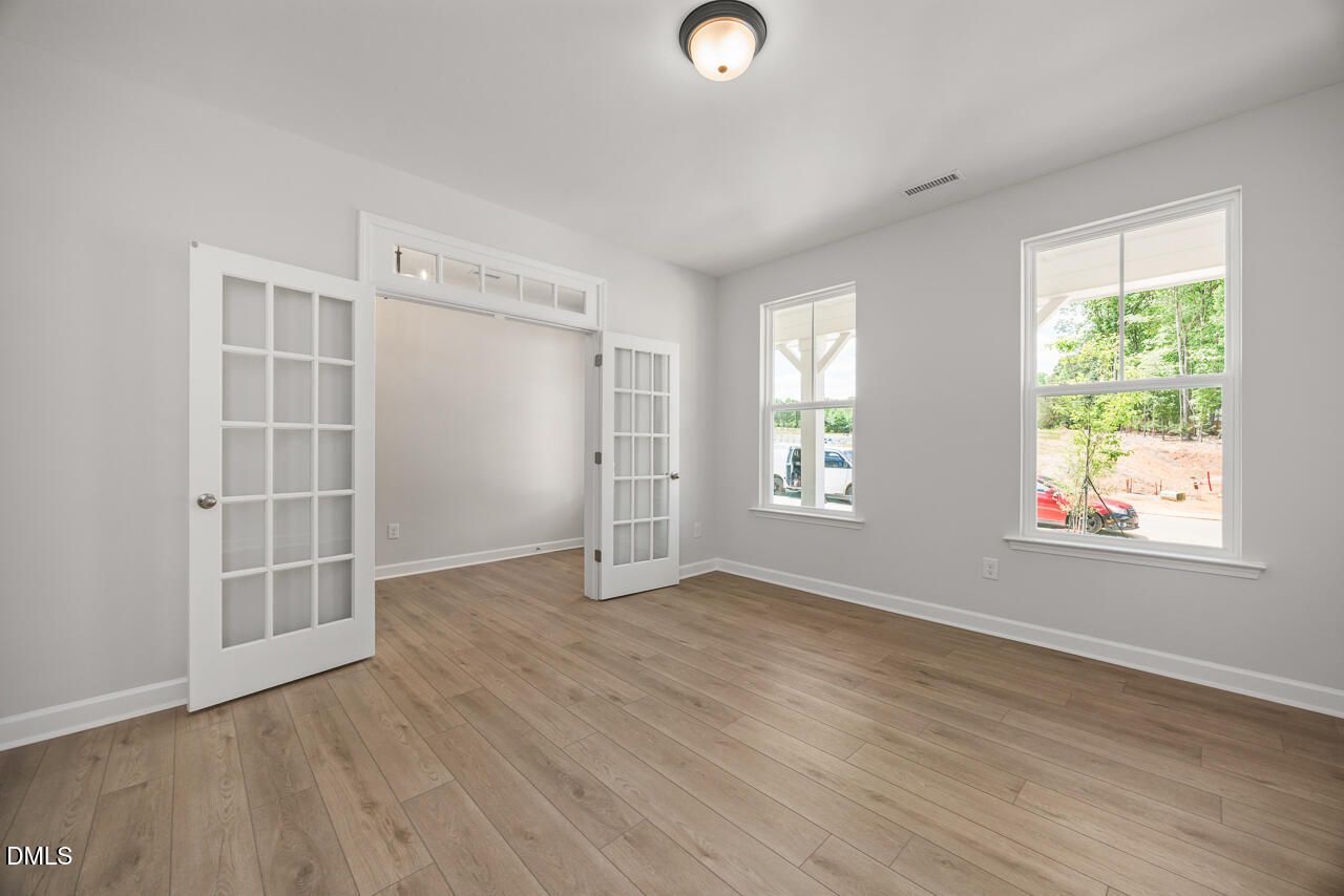 Bright home office or flex room with French doors and wood-look flooring in The Birch II E at Sage on North Main.