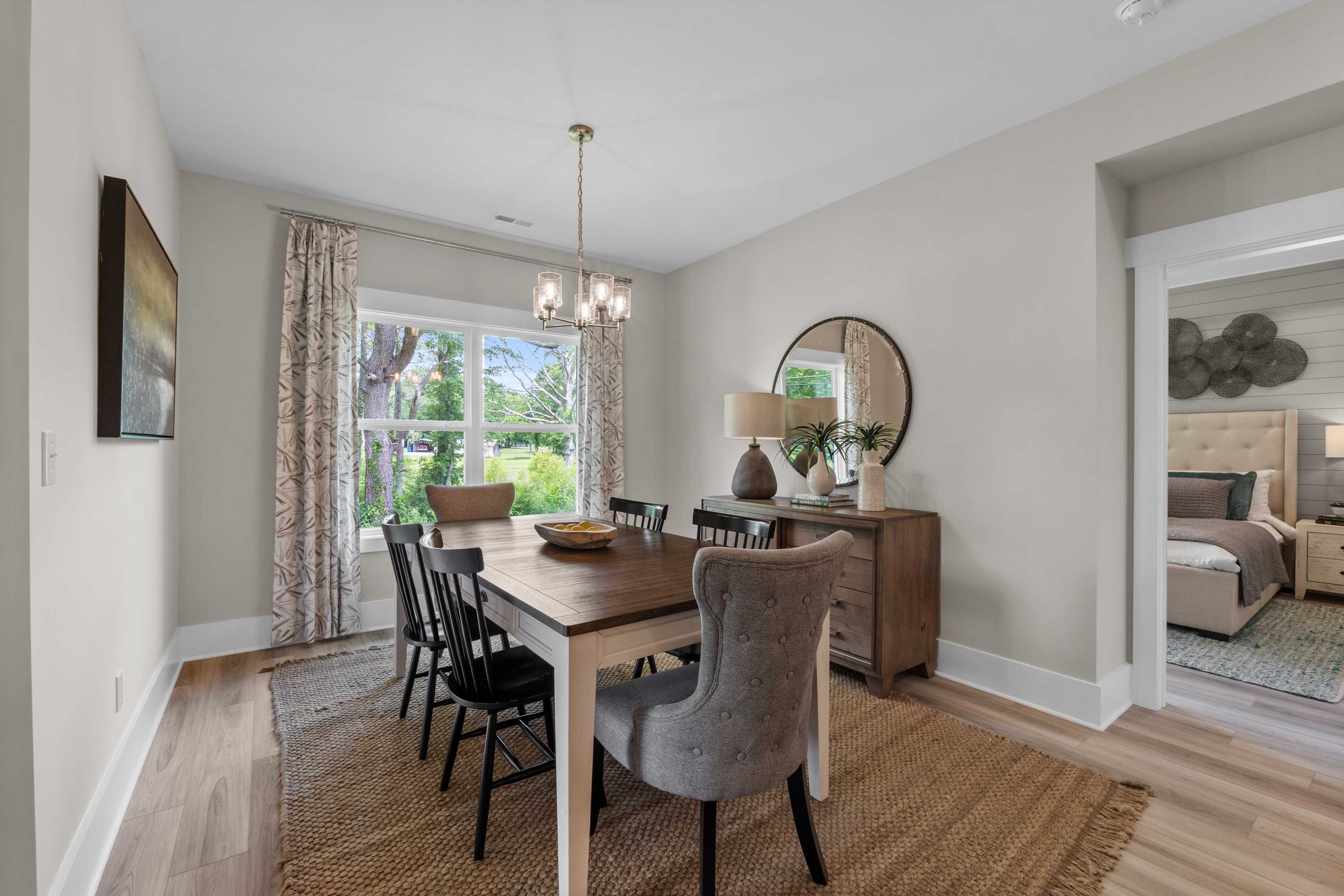 Spacious dining room at The Highlands in Arab Alabama with wooden table, gray upholstered chairs, chandelier, and open bedroom view