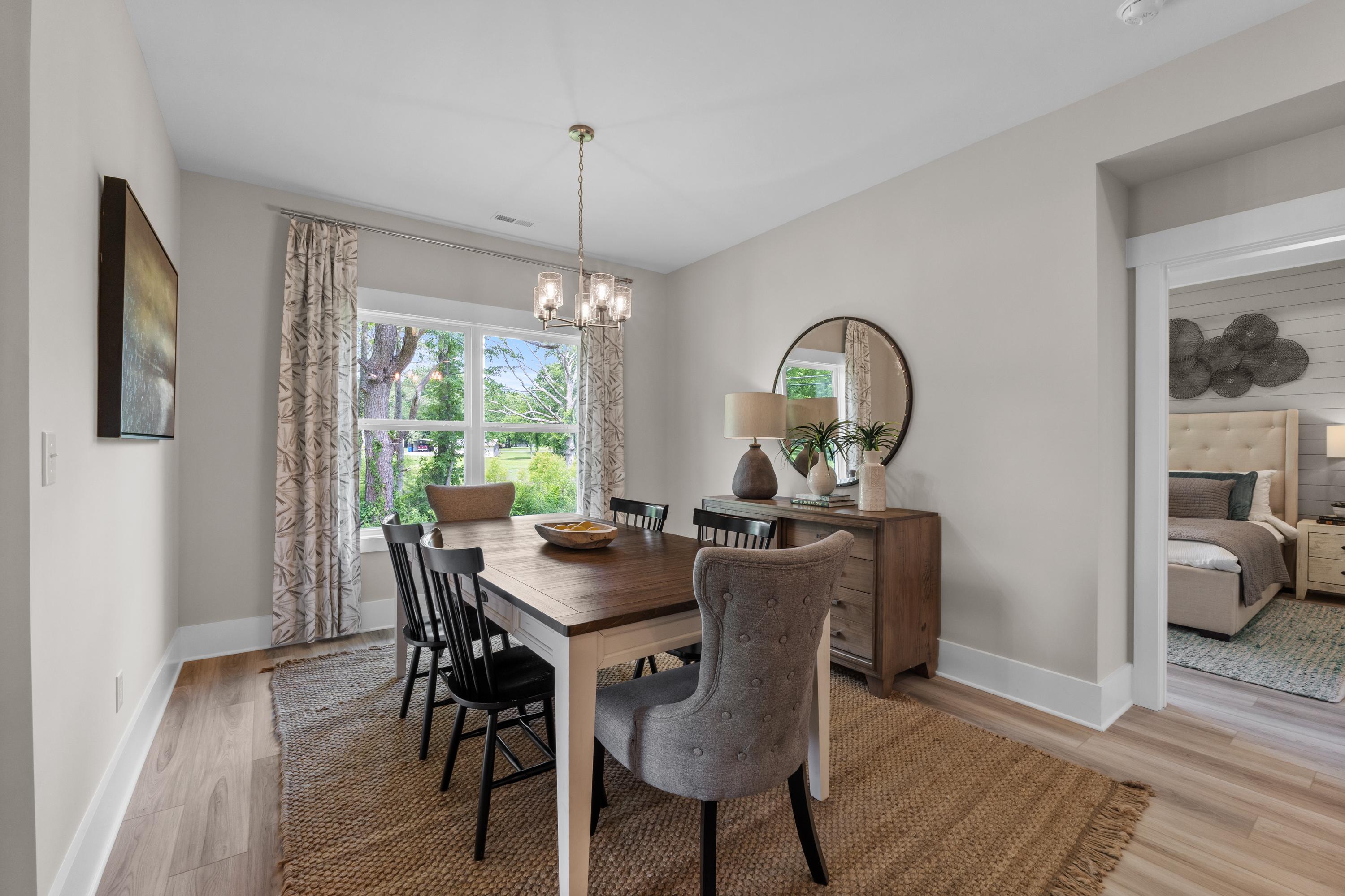 Spacious dining room at The Highlands in Arab Alabama with wooden table, gray upholstered chairs, chandelier, and open bedroom view