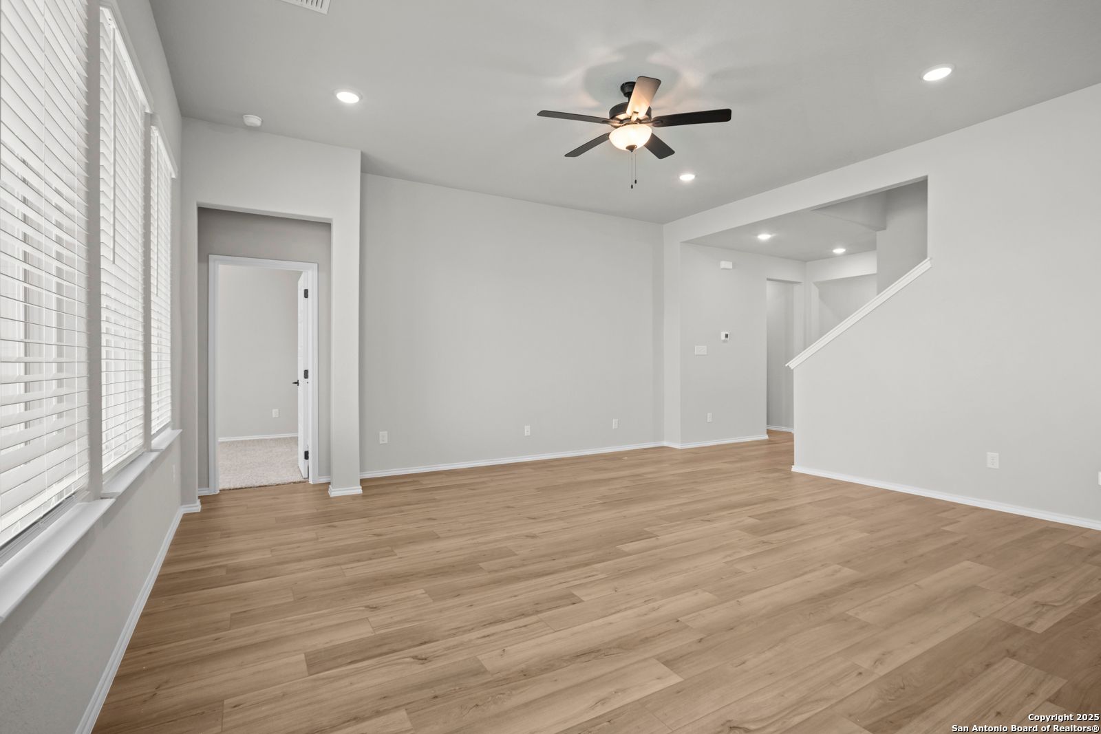 Spacious entry foyer with hardwood floors, ceiling fan, staircase, and large windows in Davidson Homes Sequoia A, Converse TX