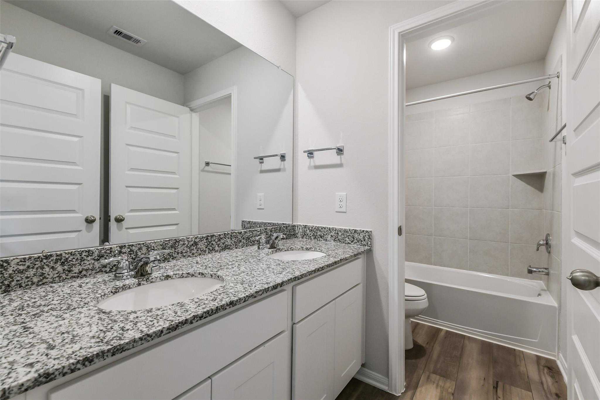 Modern master bathroom featuring double granite vanity, soaking tub, and separate shower in Davidson Homes Sabine E, Conroe TX
