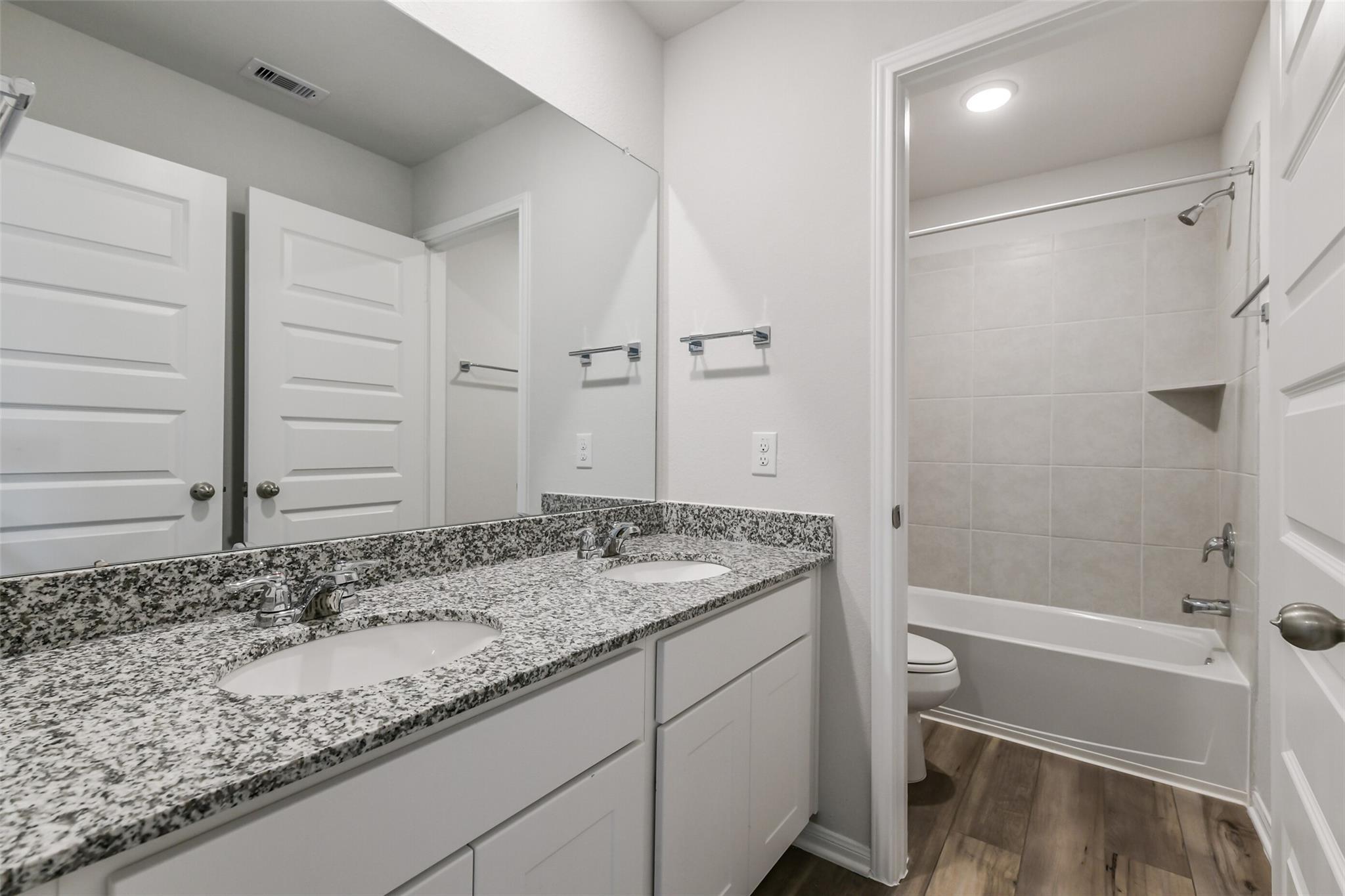 Modern master bathroom featuring double granite vanity, soaking tub, and separate shower in Davidson Homes Sabine E, Conroe TX