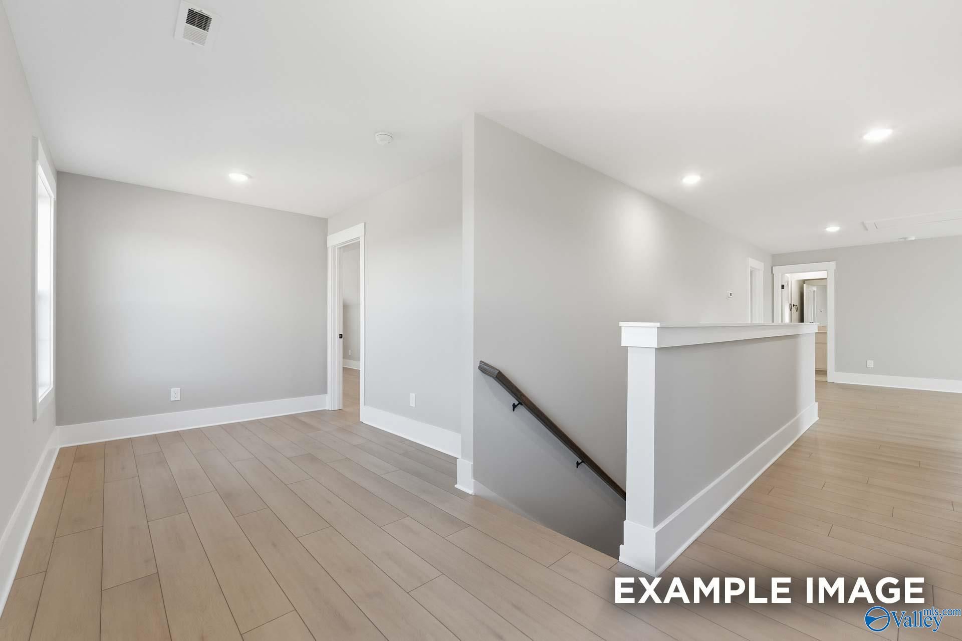 Spacious upstairs hallway with oak hardwood floors, gray walls, and modern staircase in Davidson Homes The Emory, Decatur AL
