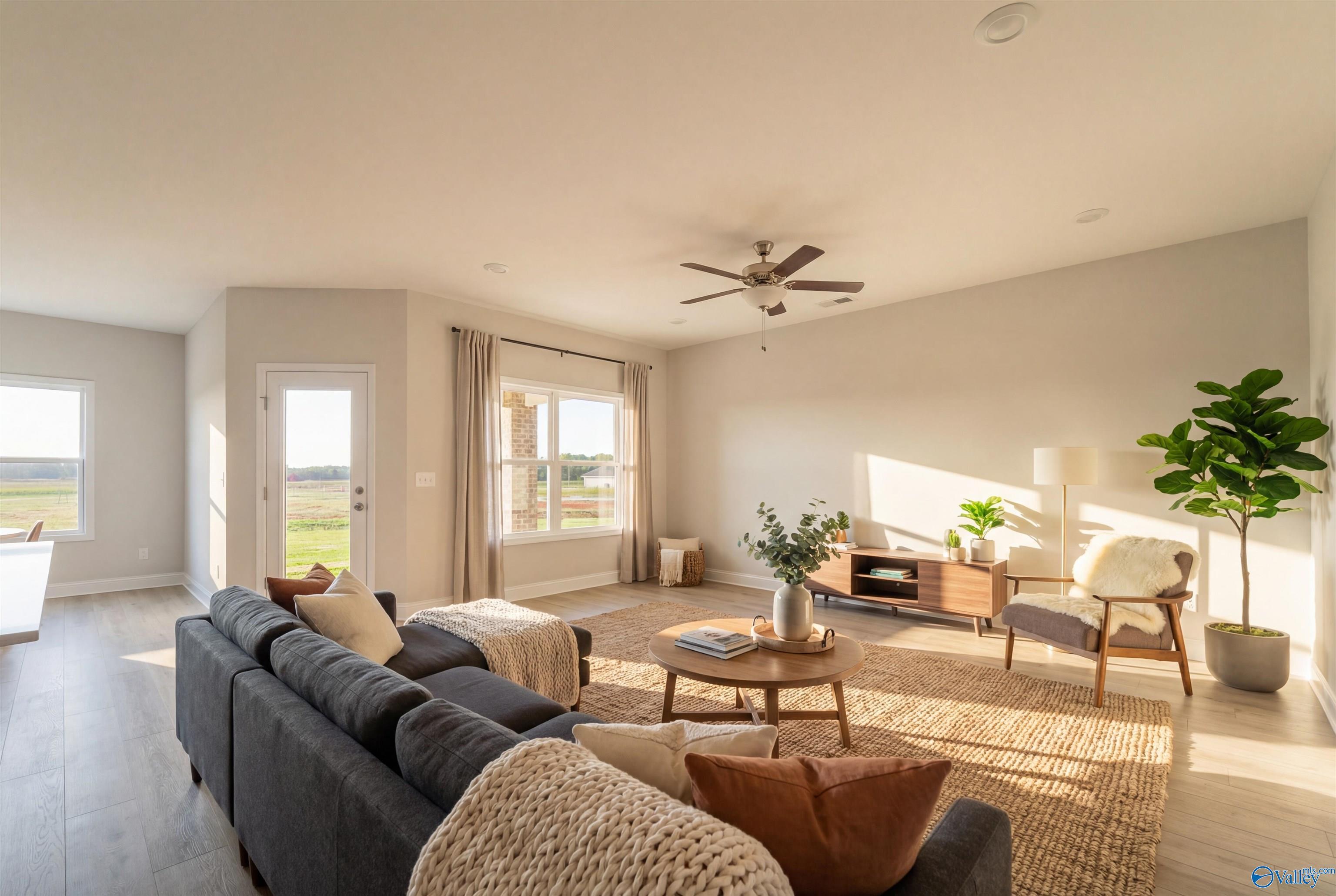 Bright living room with gray sectional sofa, wooden coffee table, fiddle leaf plant, and large windows in Davidson Homes The Everett, Hazel Green