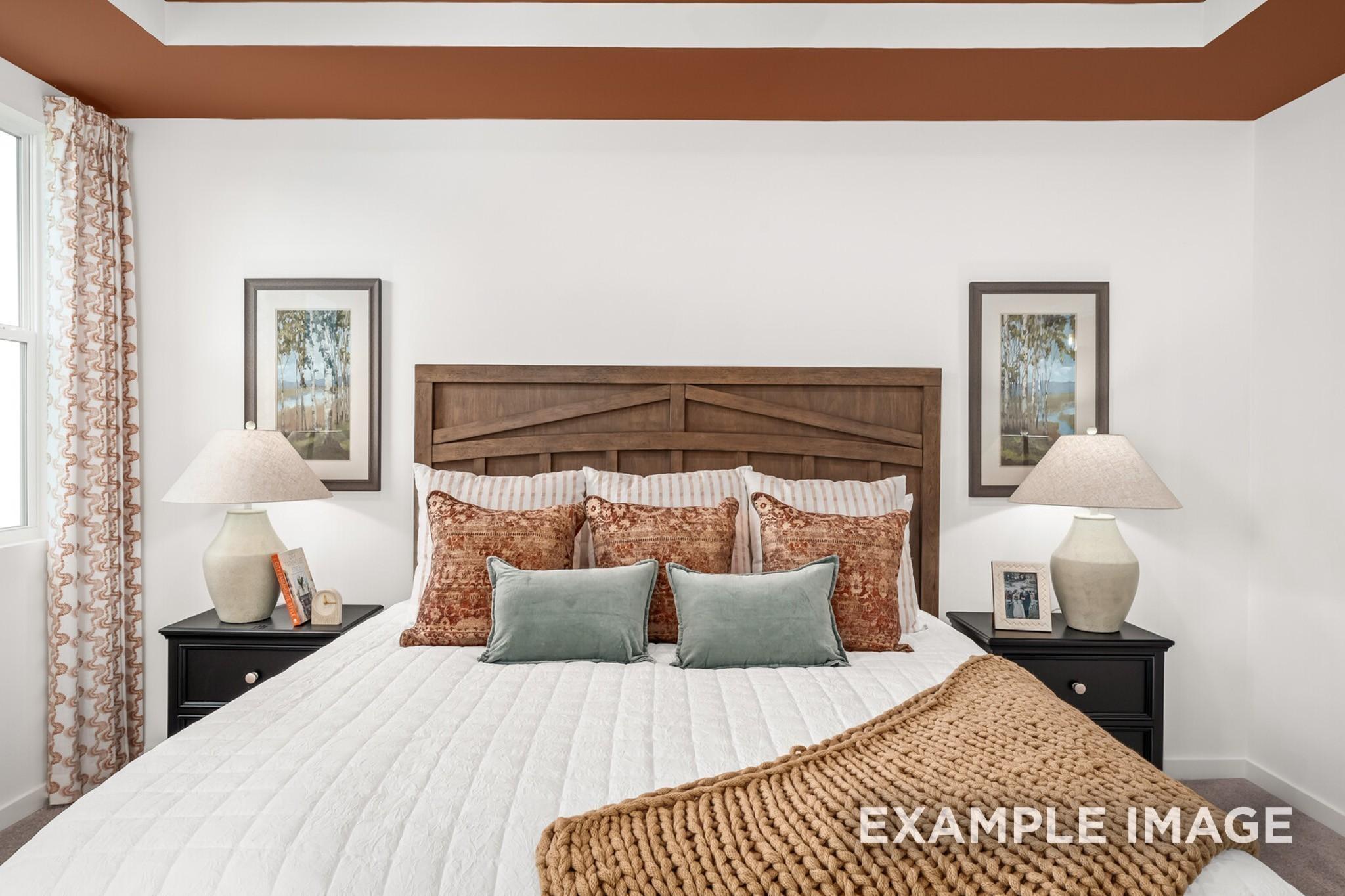 Cozy bedroom with wooden headboard and tray ceiling in The Ash A floor plan at Woods Crossing, Gallatin, Tennessee.
