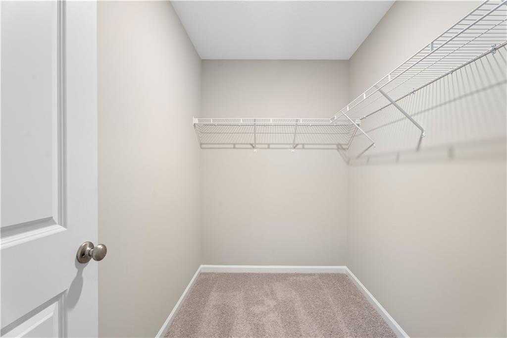 Spacious walk-in closet with wire shelving and beige carpet in Davidson Homes The Washington, Phenix City, Alabama