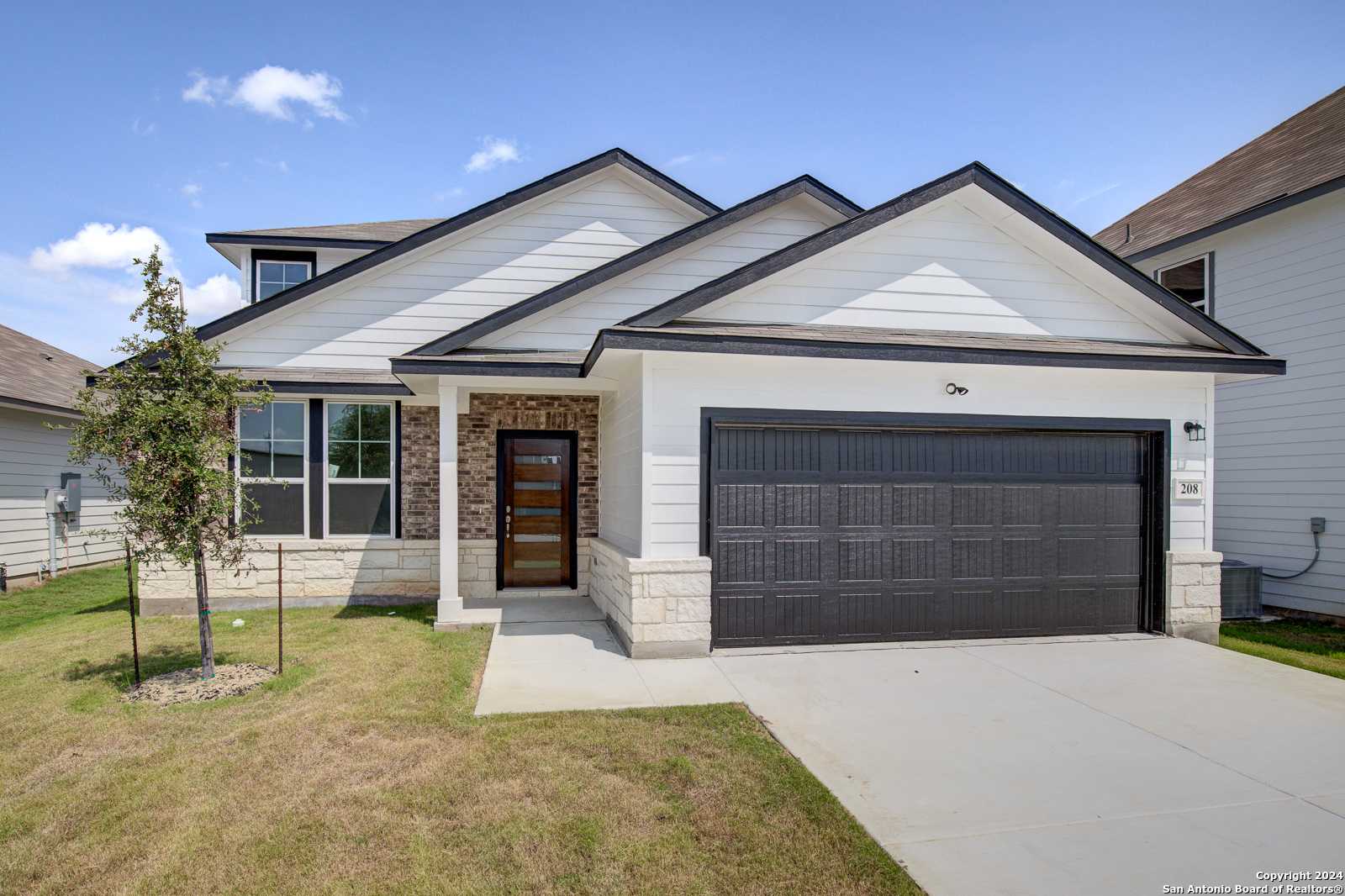 Two-story Douglas D home by Davidson Homes with white siding, black garage door, and covered porch in Hannah Heights, Seguin, Texas