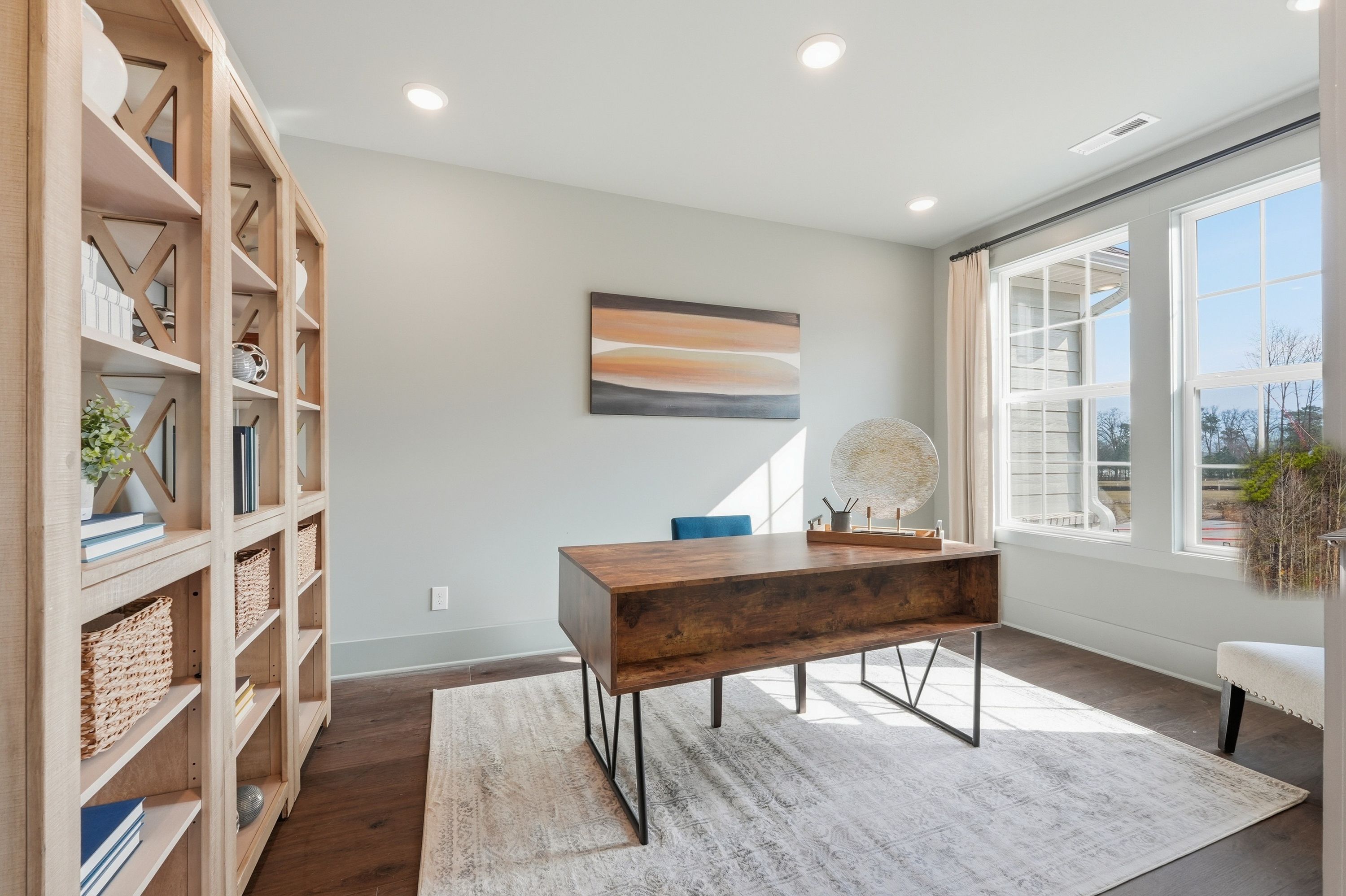 Spacious home office at Noble Ridge in Cullman, Alabama with wooden bookshelves, large desk, and large windows