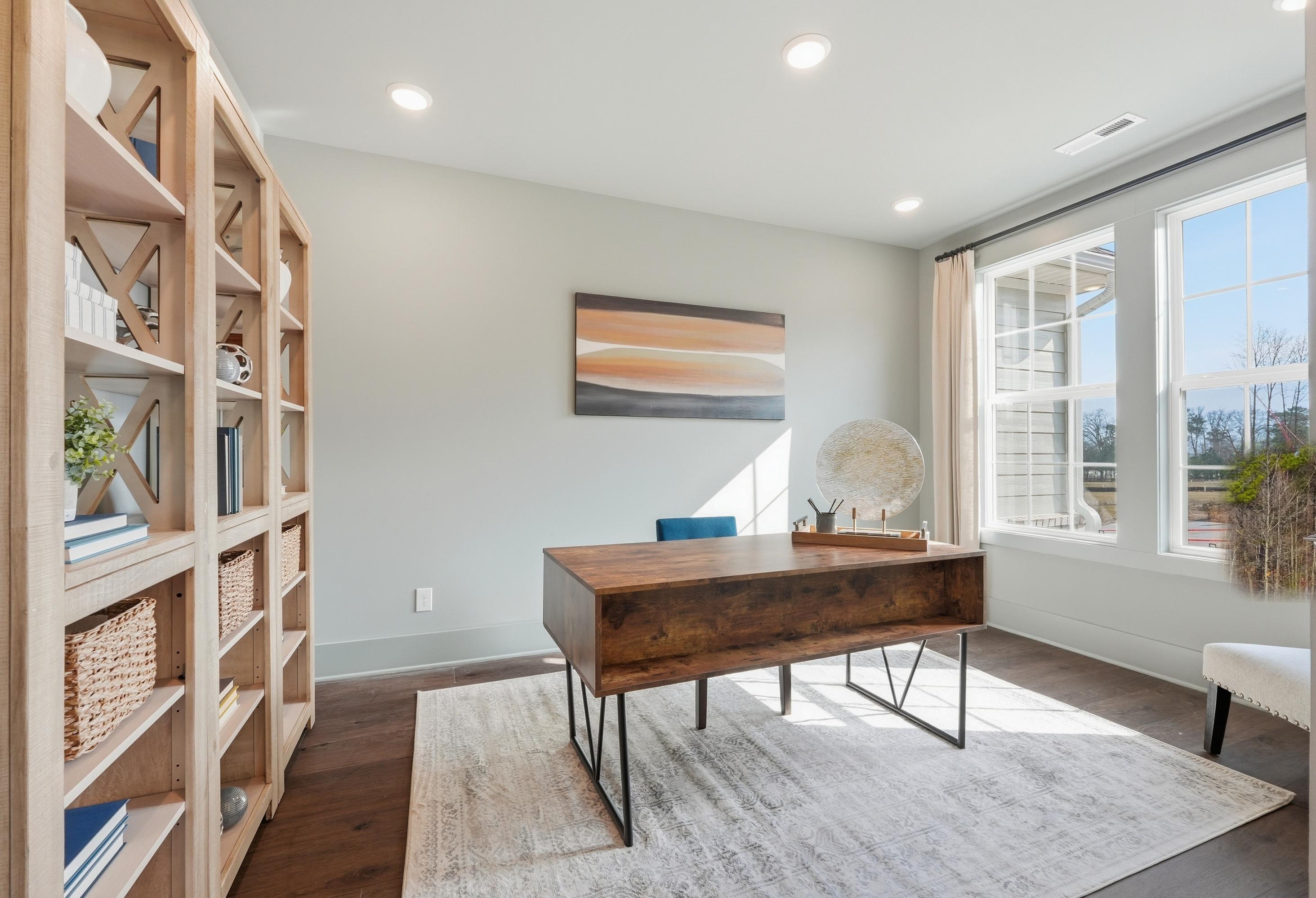 Modern home office in The Hibiscus floor plan featuring a wooden desk, bookshelf, and natural light in Cullman, Alabama.