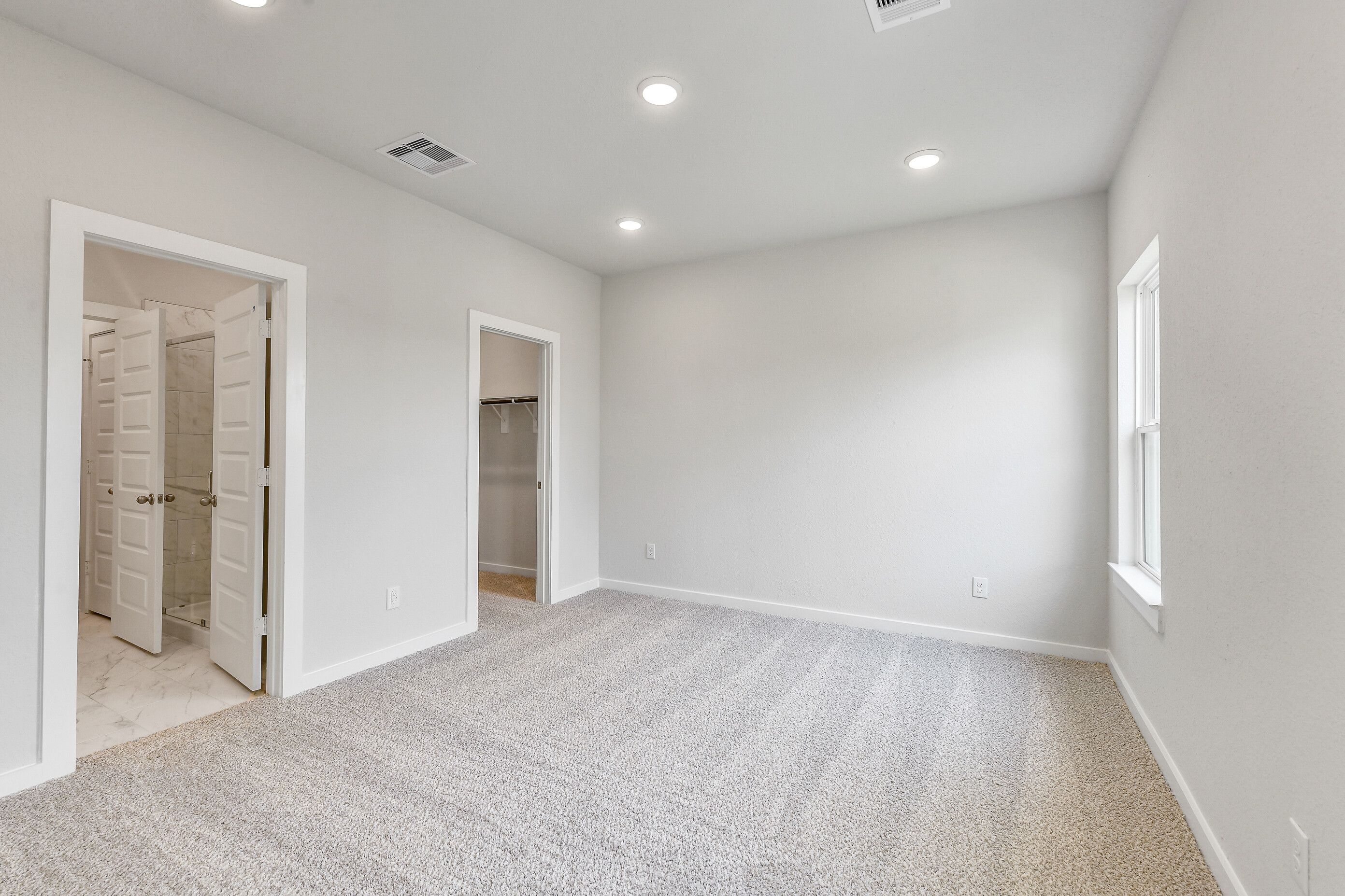 Spacious carpeted bedroom with en-suite bath, marble floor, glass shower, and walk-in closet in Davidson Homes The Colorado G, Magnolia TX
