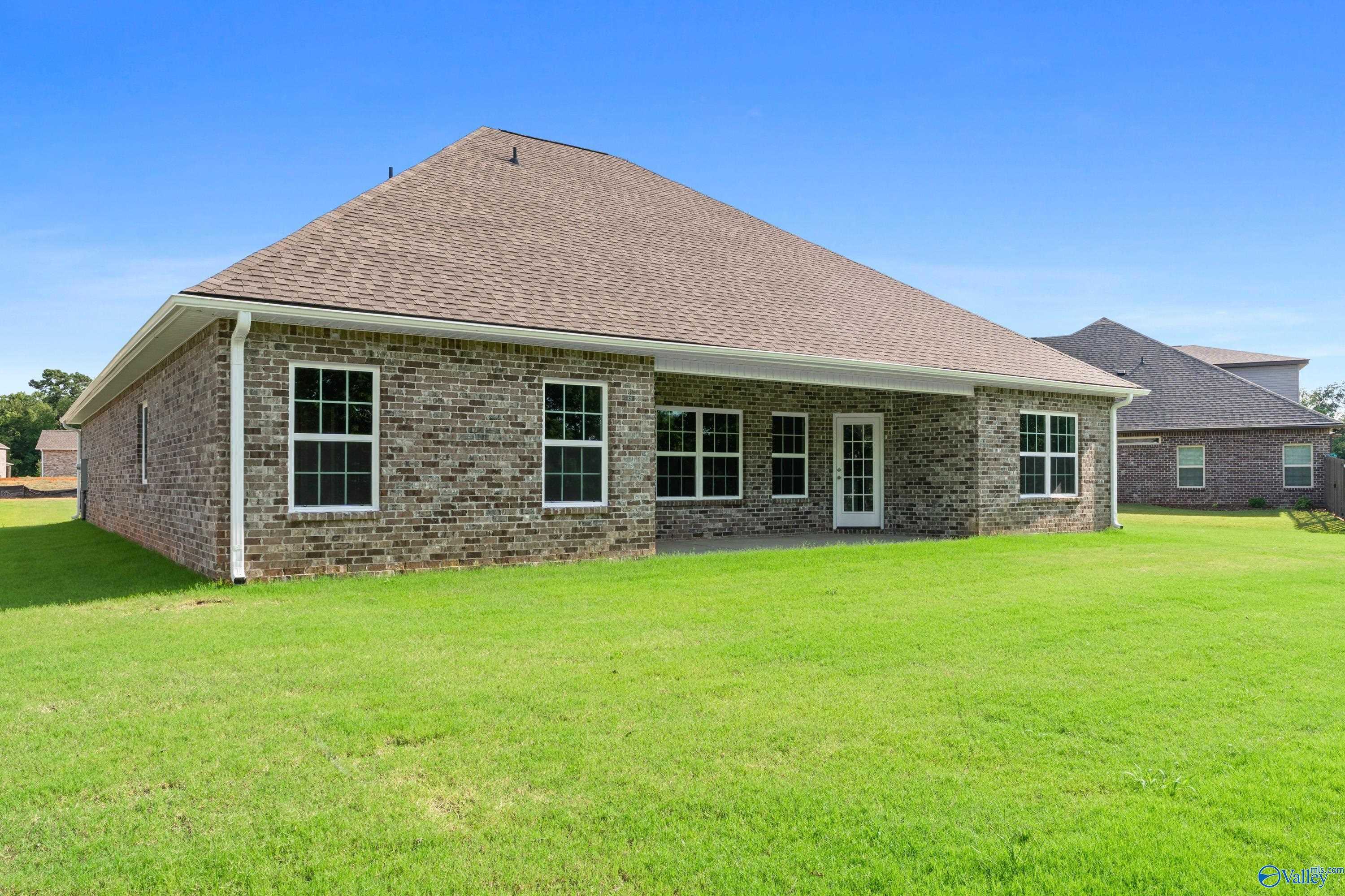 Brick exterior of Davidson Homes The Rockford with covered back patio and lush green lawn in Creekside, Harvest, Alabama