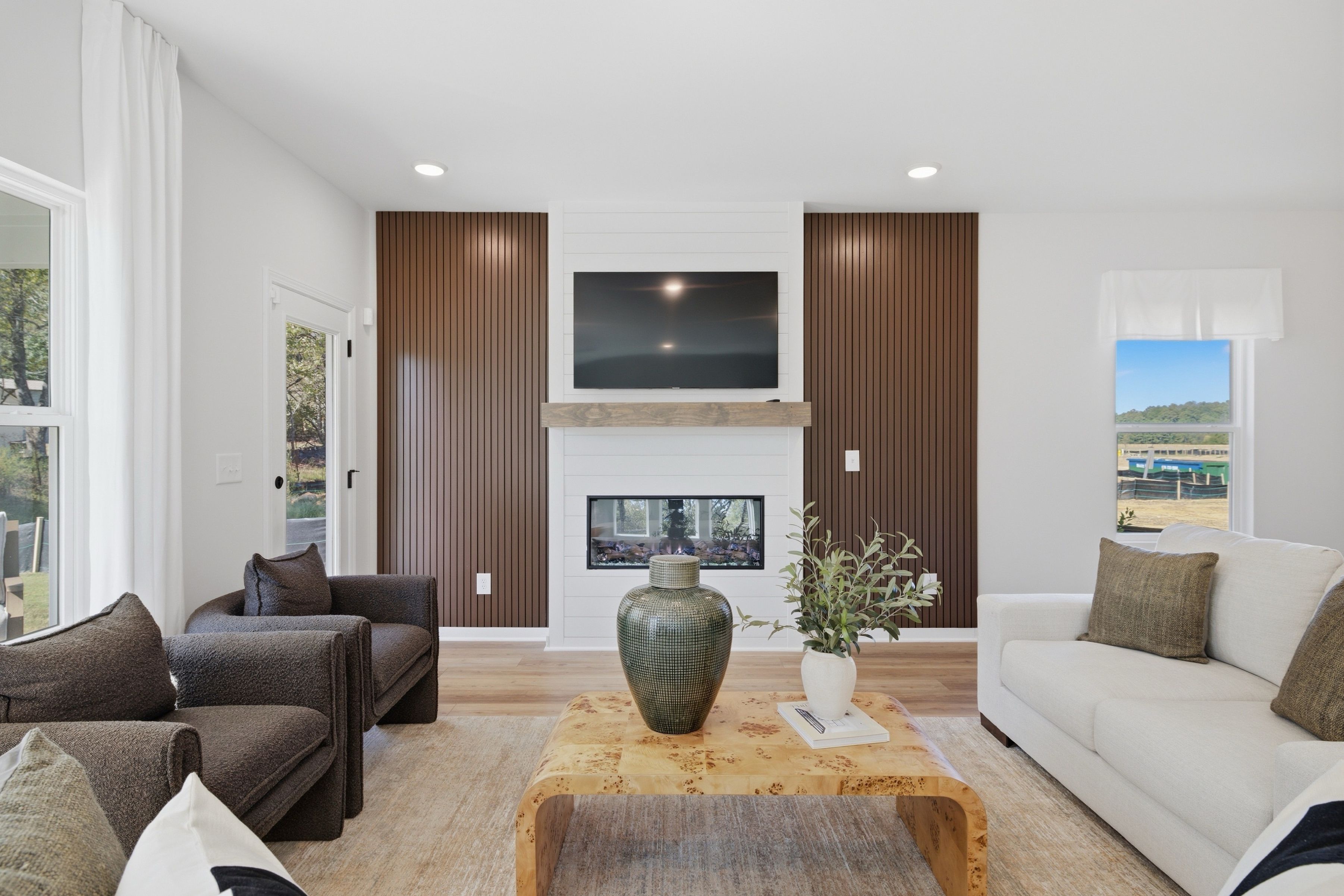 Great room living area at Greene Farm in Cartersville, GA by Davidson Homes with linear fireplace, wood accent walls, and white sofa