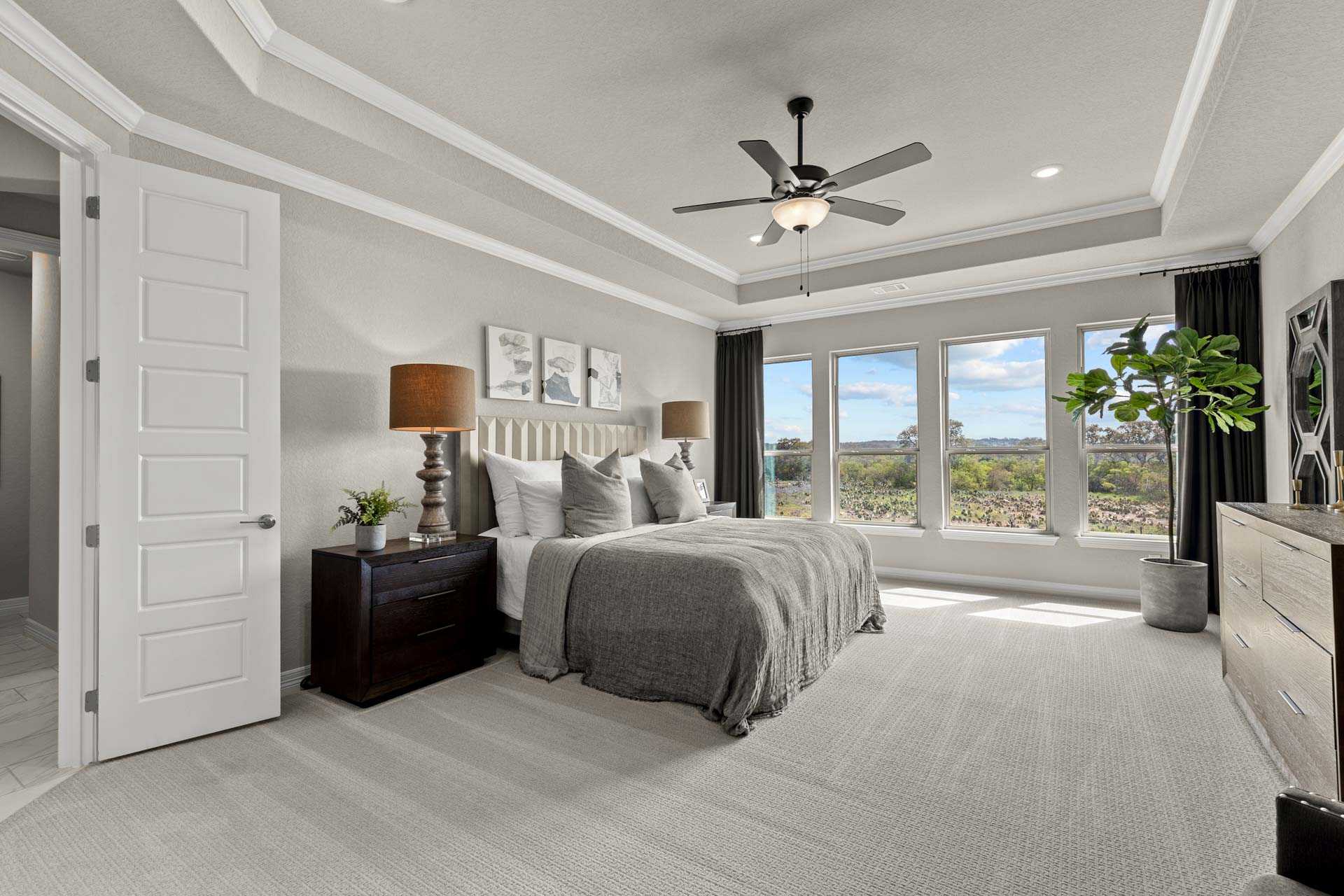 Spacious master bedroom in The Summerlin B featuring king bed, neutral gray tones, large windows, and ceiling fan