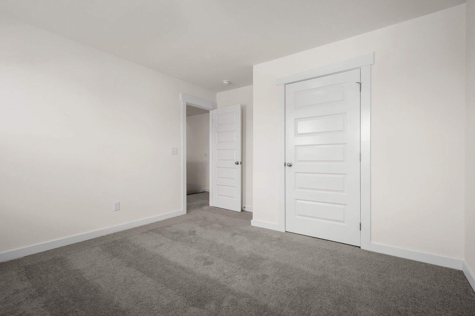 Bright bedroom with neutral carpet and white doors in The Ash A floor plan at Woods Crossing, Gallatin, Tennessee.