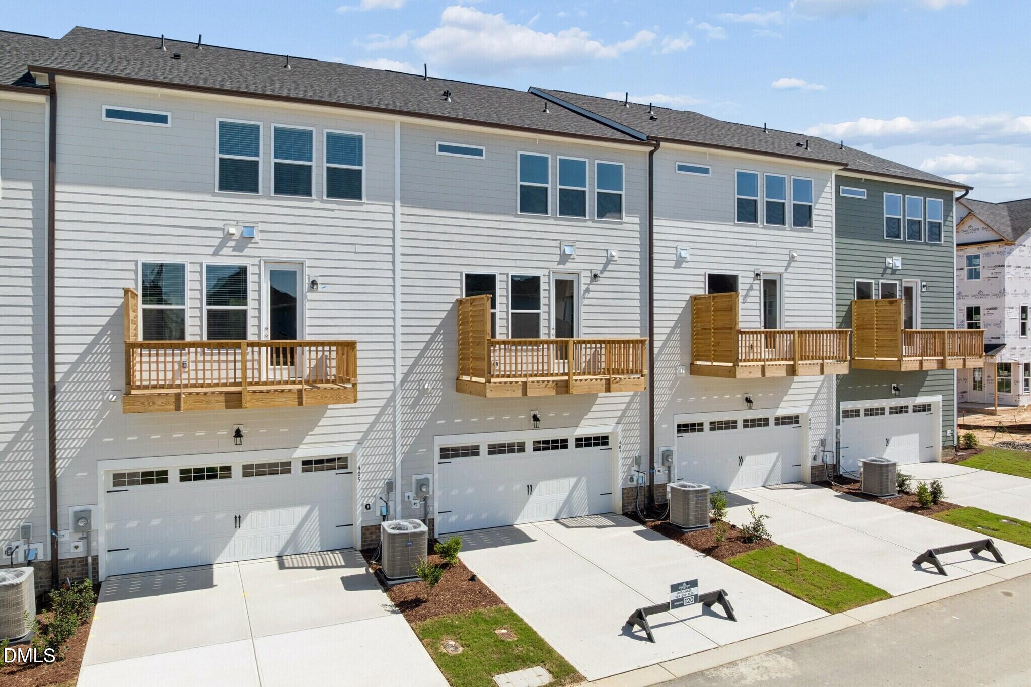 Rear exterior of 3-story townhomes with wooden balconies and 2-car garages at Forestville Yard, Knightdale, North Carolina