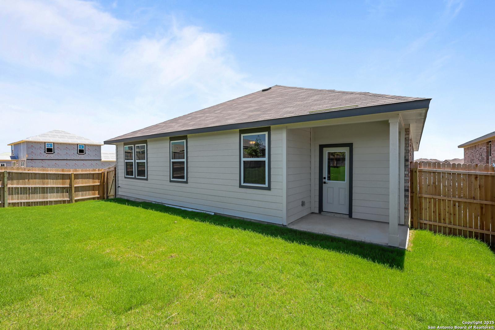 Modern single-story 4-bedroom home exterior with covered porch, green lawn, and fence in Comanche Ridge, San Antonio, Texas