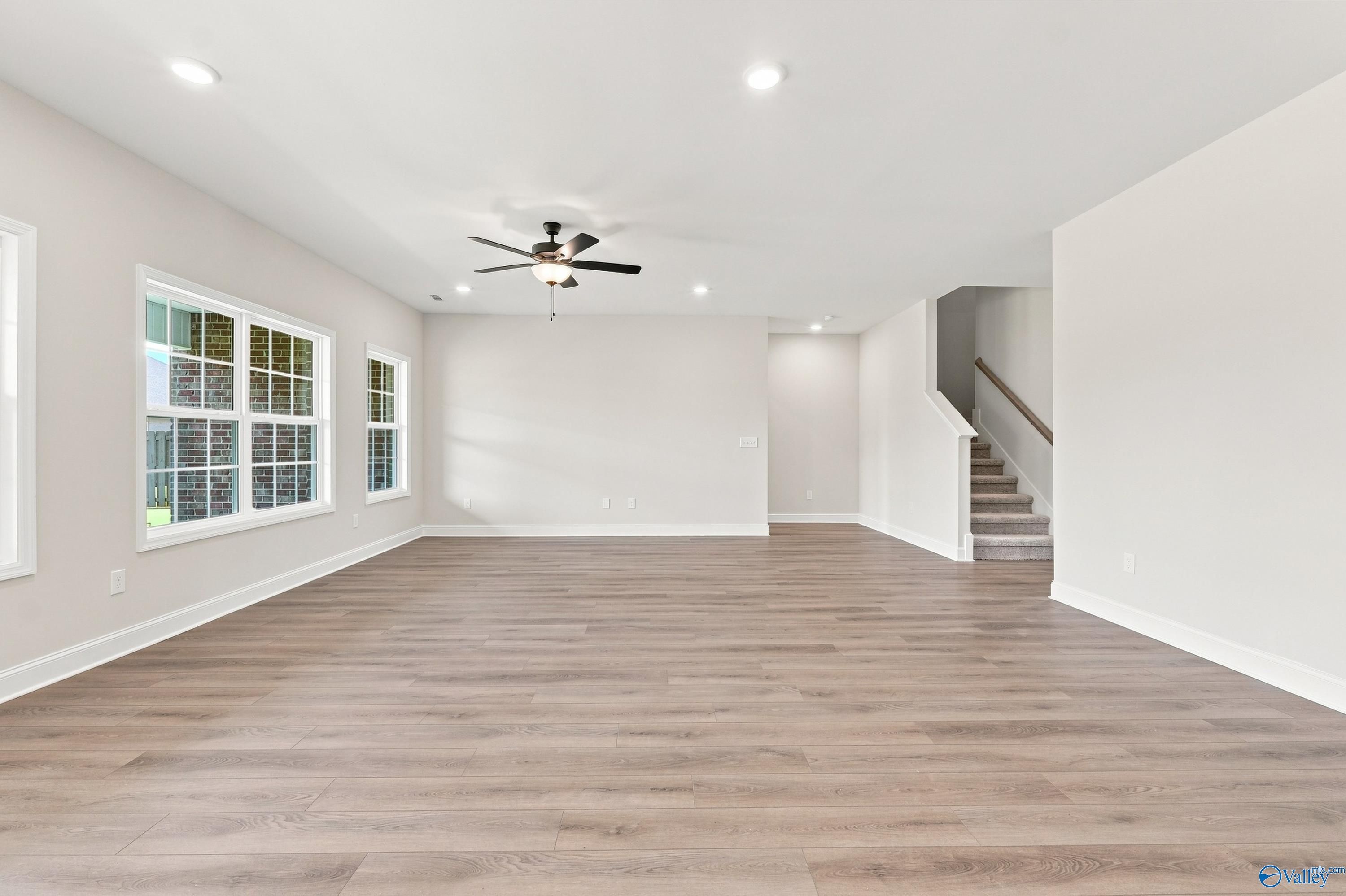 Spacious open-concept living area with wood-style flooring in The Rockford B floor plan at Kendall Downs in Toney, Alabama.