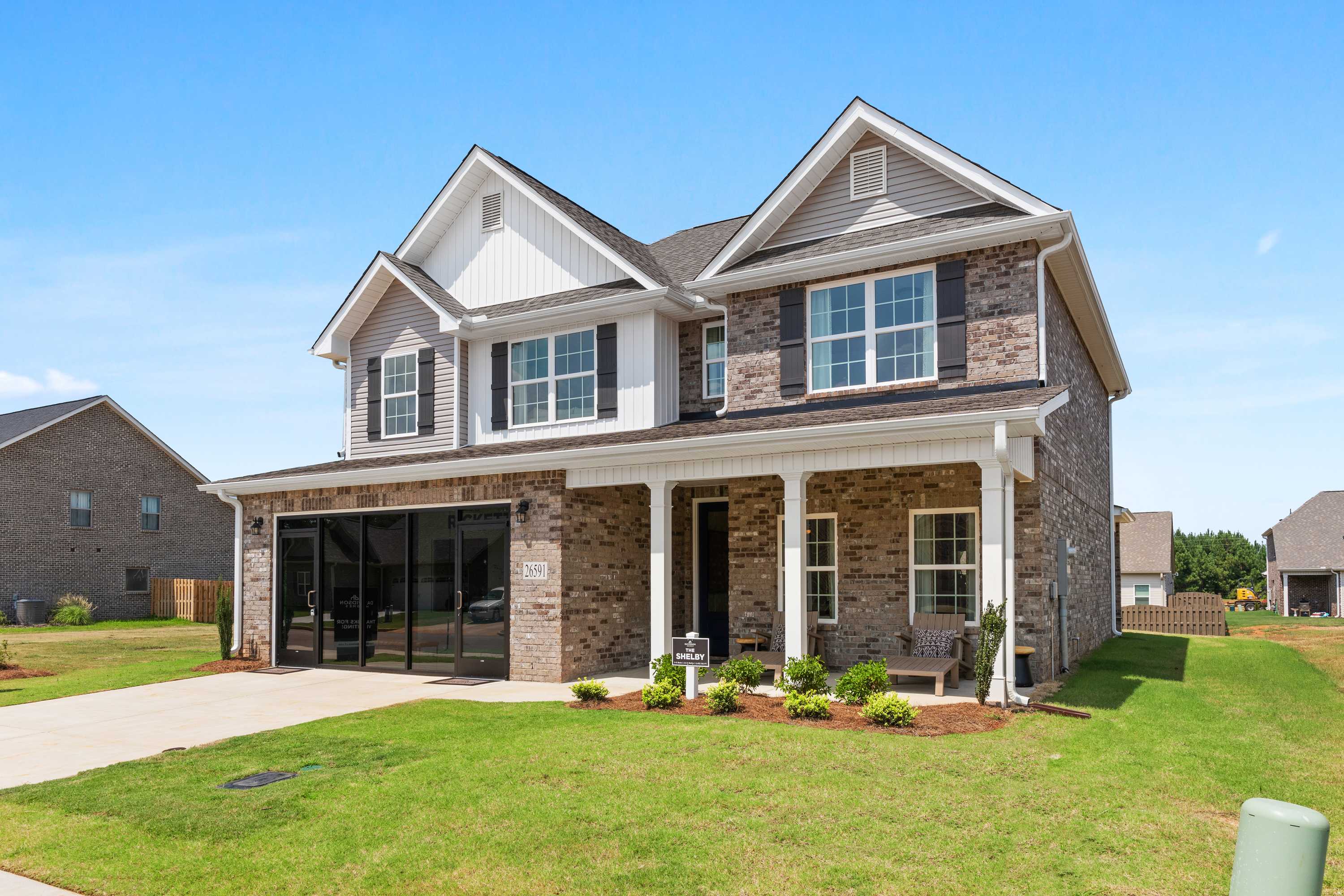 Craftsman brick home exterior at Ricketts Farm in Athens Alabama with covered front porch, columns, and landscaped yard
