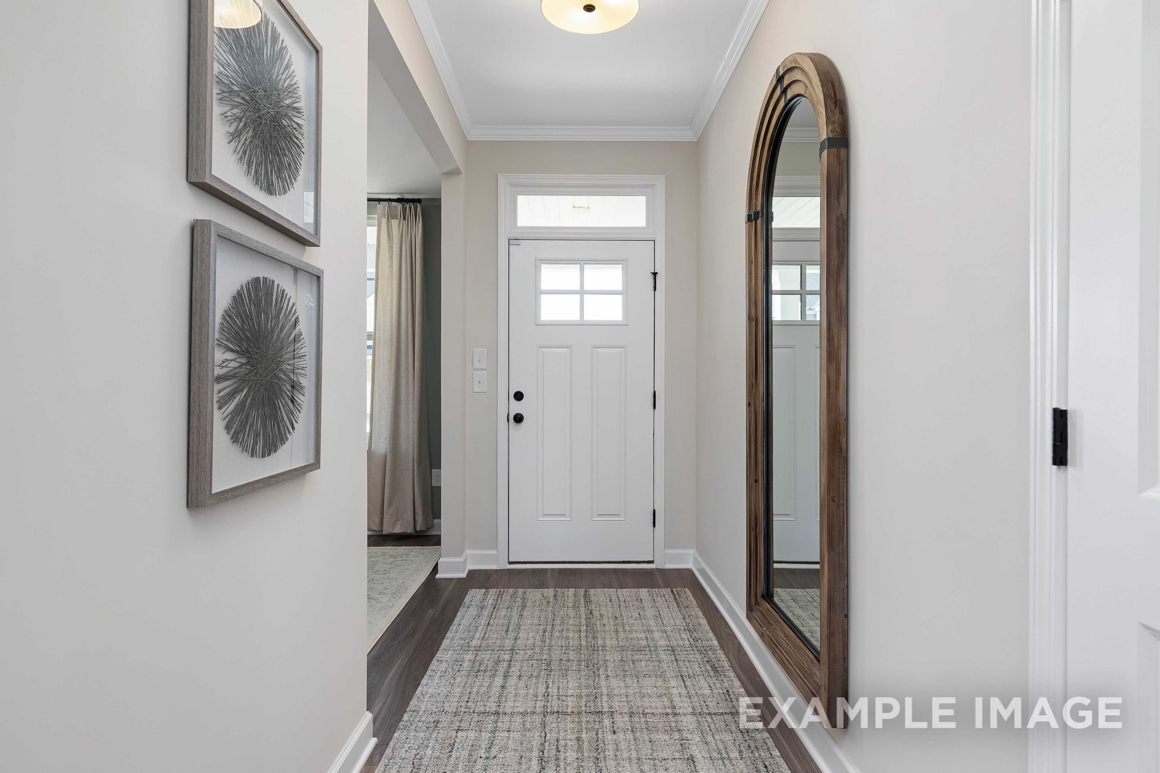 Elegant hallway in The Willow B home by Davidson Homes, Wendell NC, with arched wooden mirror, white door, and neutral walls